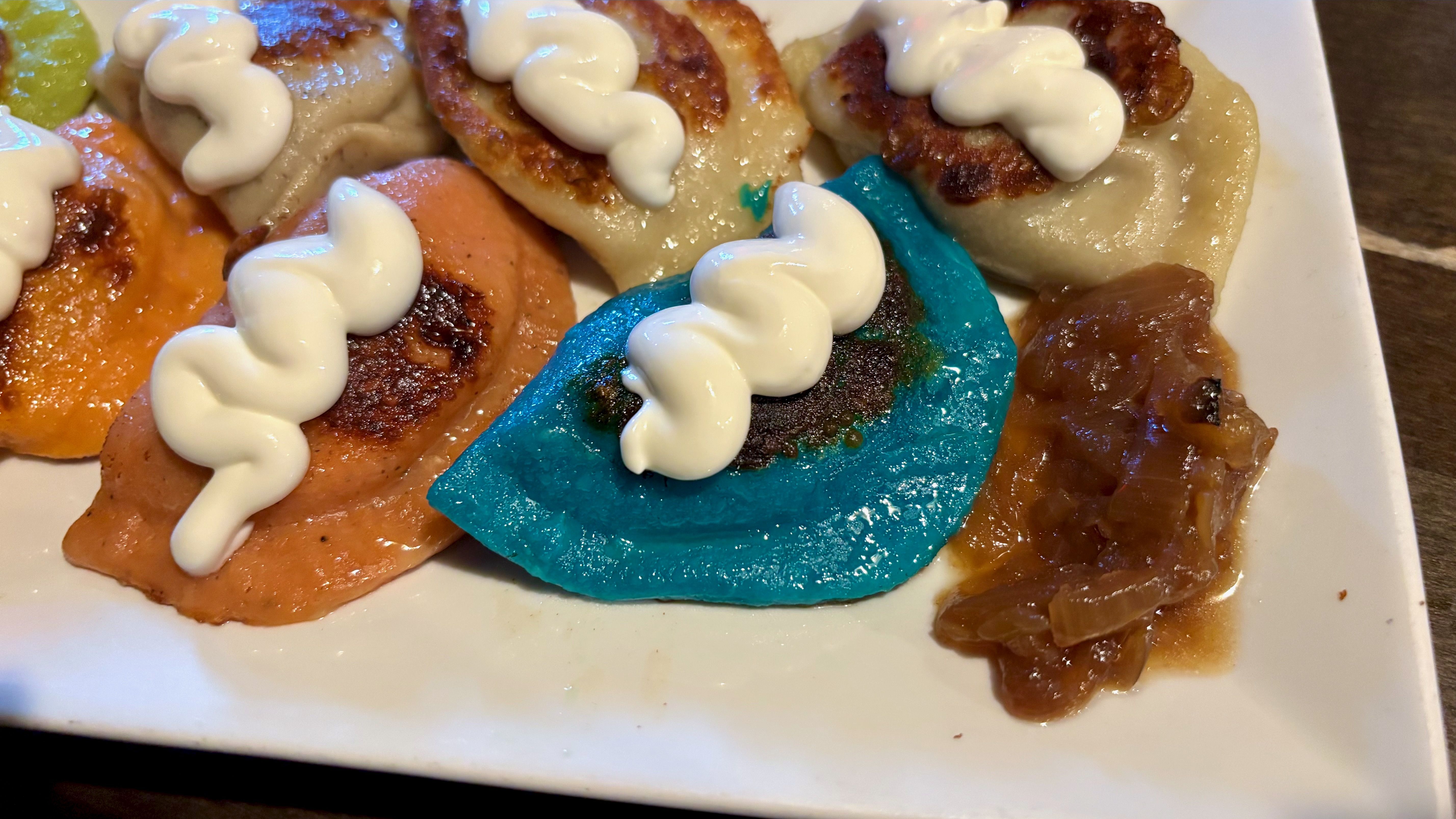 A close-up of the cool ranch blue pierogi with a zigzag dollop of sour cream on it.