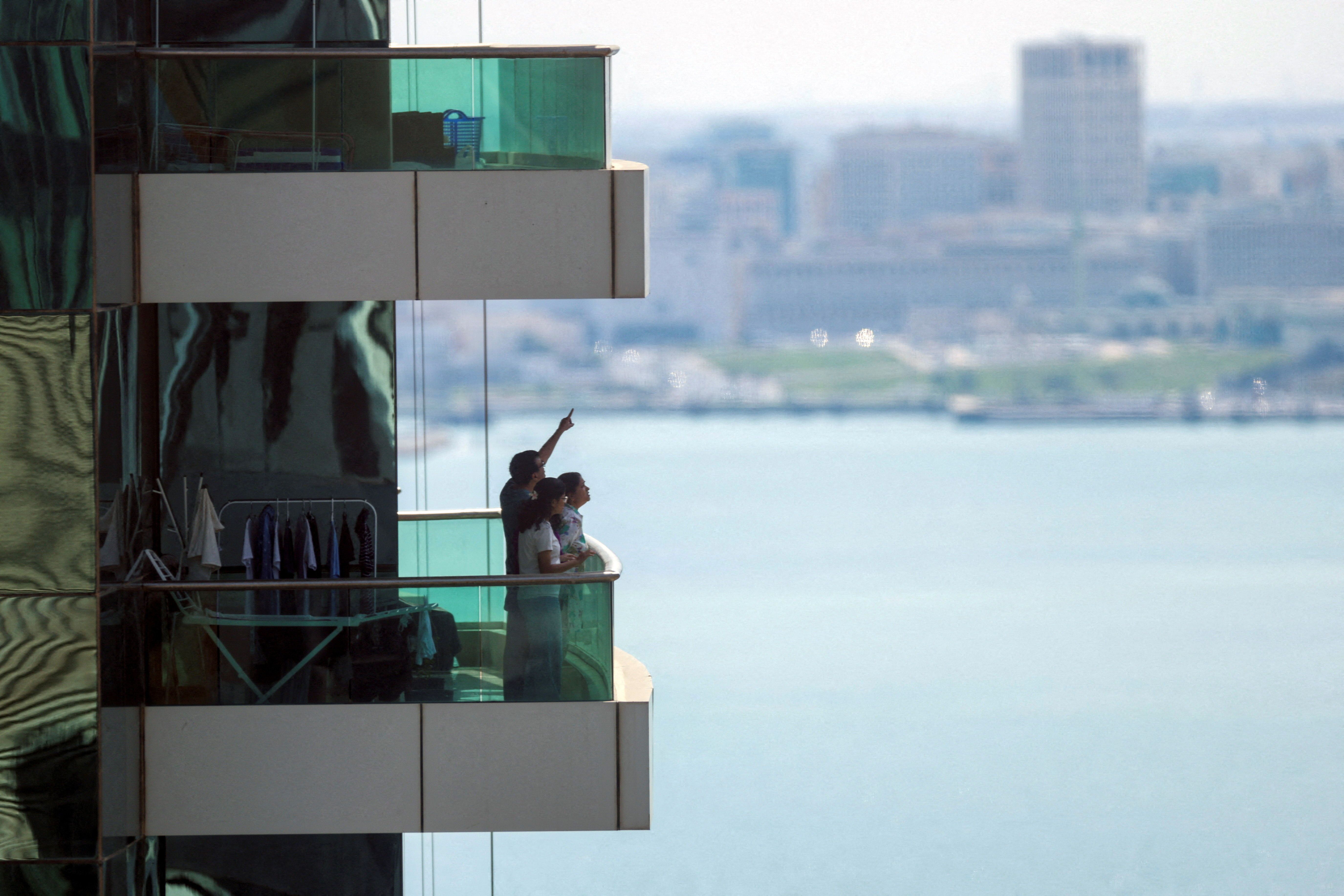 People watch from their balcony amid explosions today in Doha, Qatar. The defense ministry says it has downed missiles targeting the country. Photo: Mohmmed Salem/Reuters