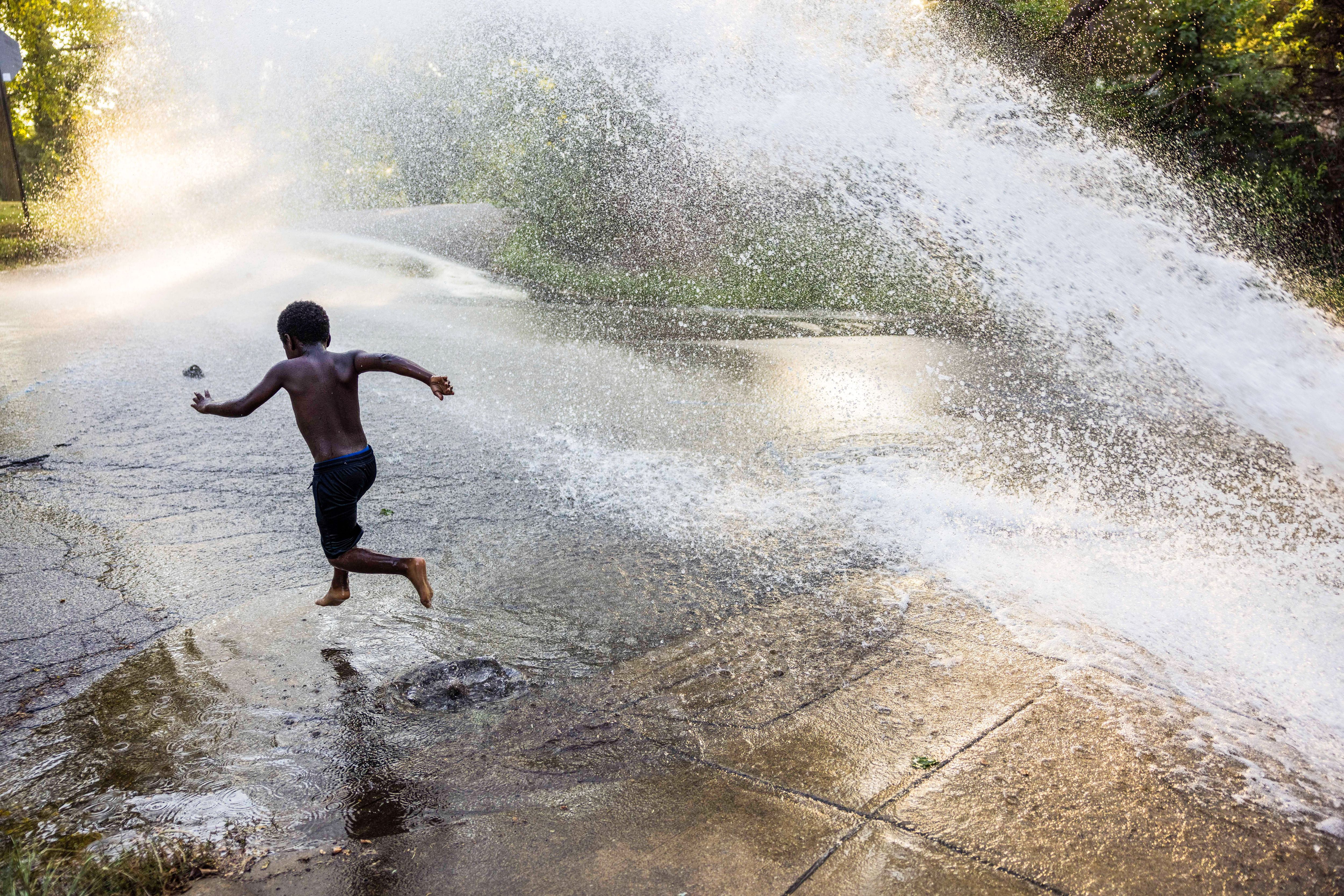 A child plays in fire hydrant water in Bloomington, Indiana, in 2021.