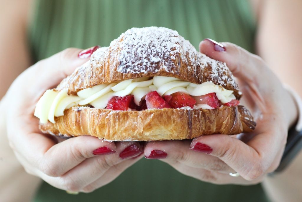 A croissant with strawberries and piped icing in the middle. 