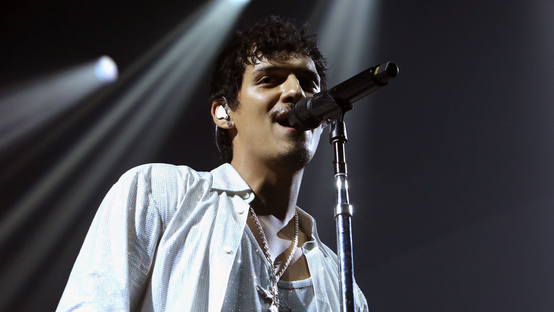 A photo of a person singing into a microphone.