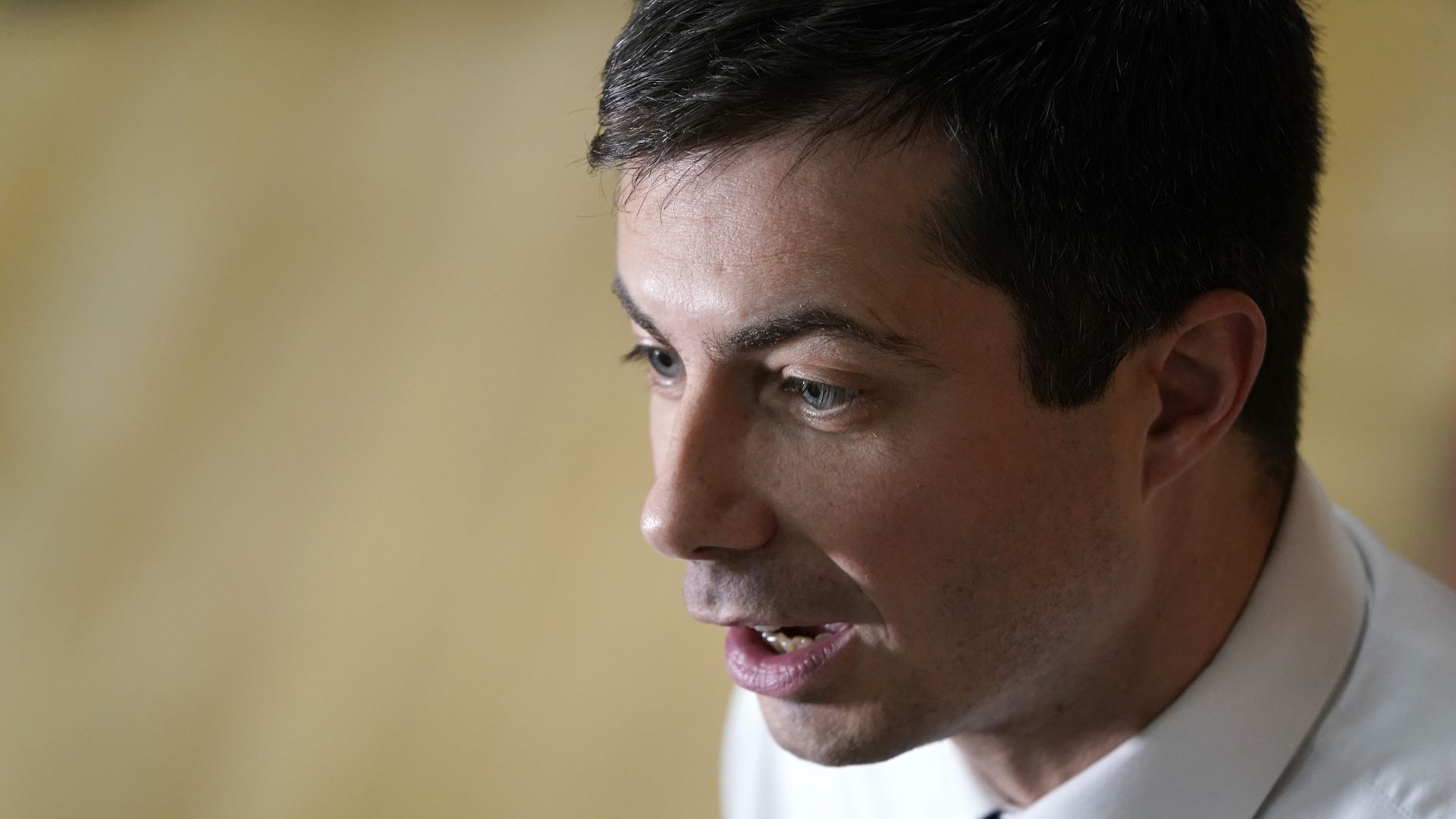 In this image, Pete Buttigieg talks while wearing a shirt and tie.