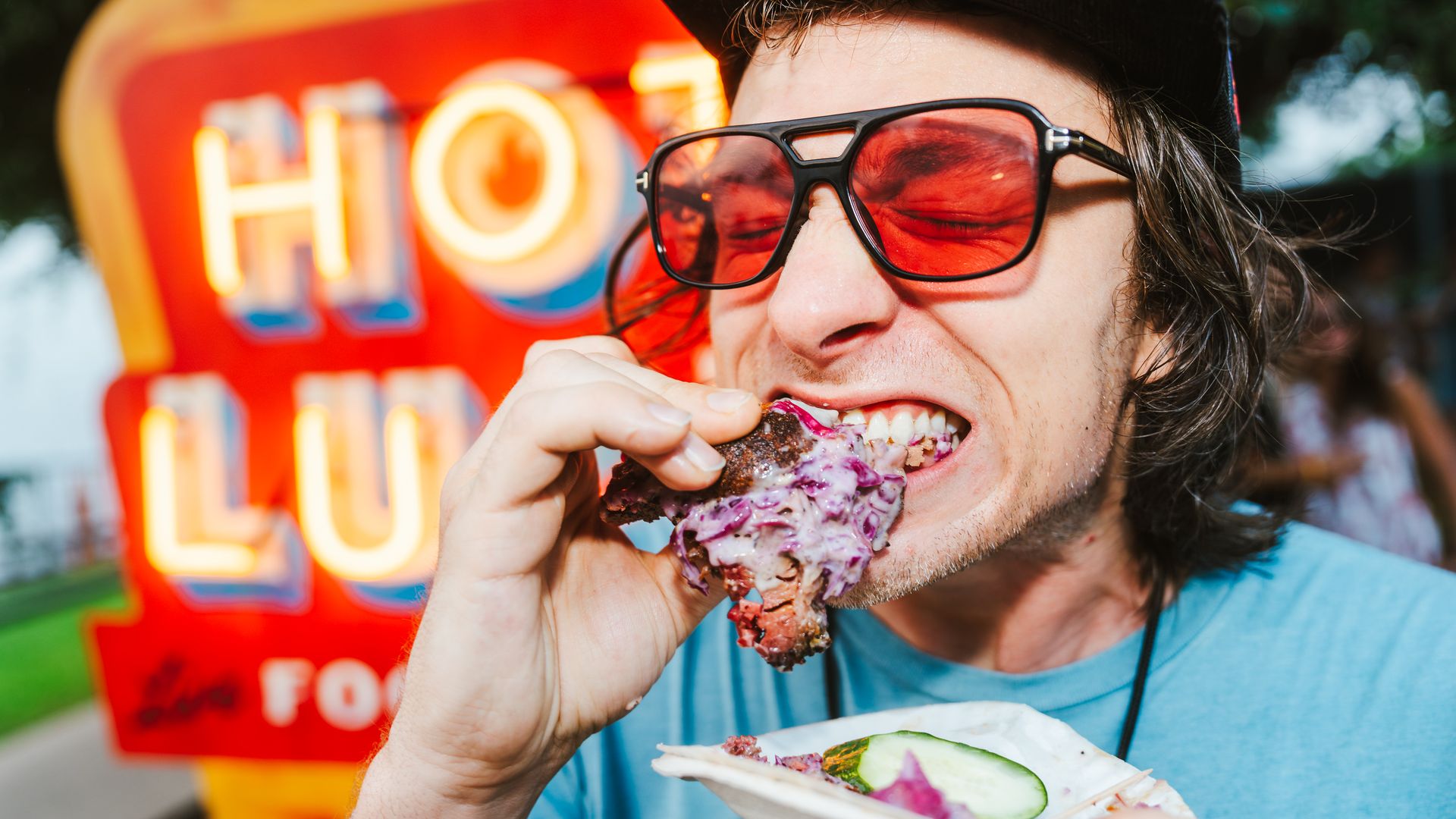 A person biting into food at the Hot Luck Festival.