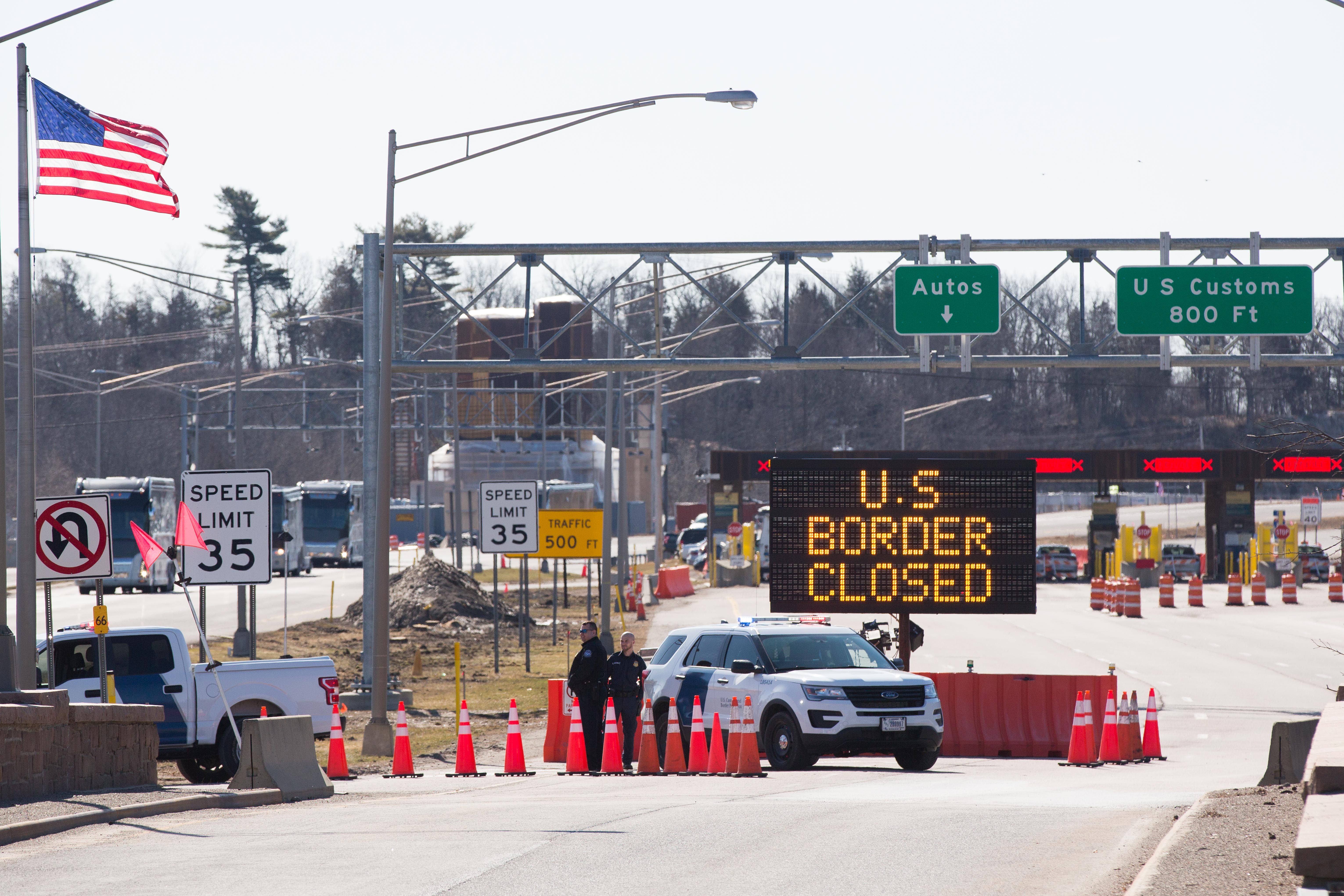US Customs officers stand beside a sign saying that the US border is closed at the US/Canada border 