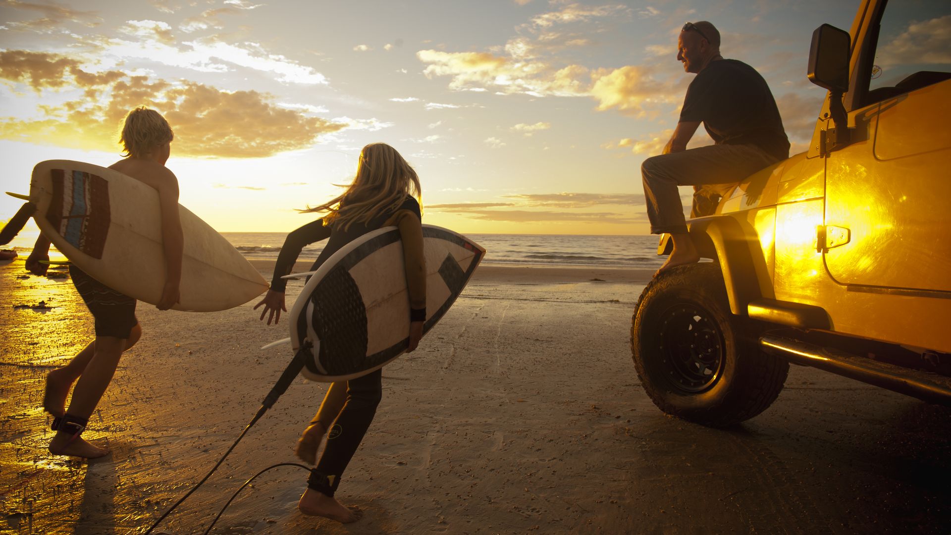 Kids running to the water with their surfboards