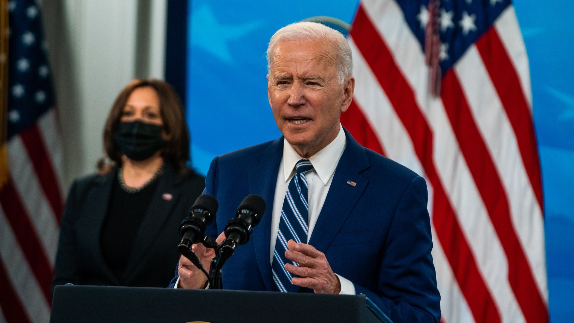 Joe Biden stands in front of an American flag and Kamala Harris