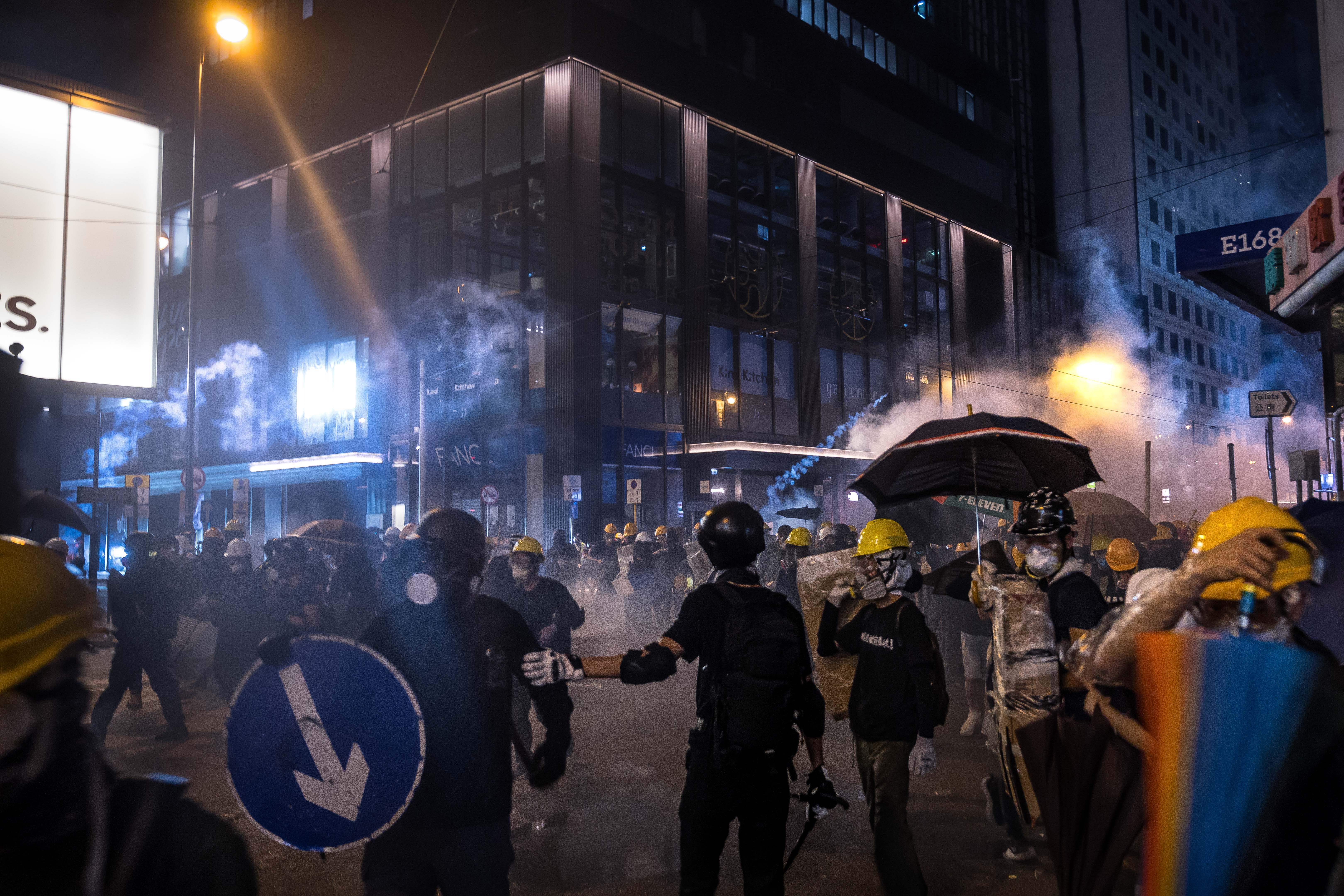 Protesters are enveloped by tear gas on street during a demonstration in the area of Sheung Wan