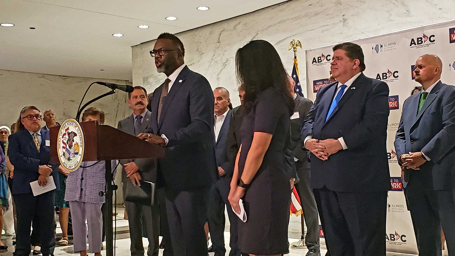 Photo of a man speaking at a podium during a press conference. 