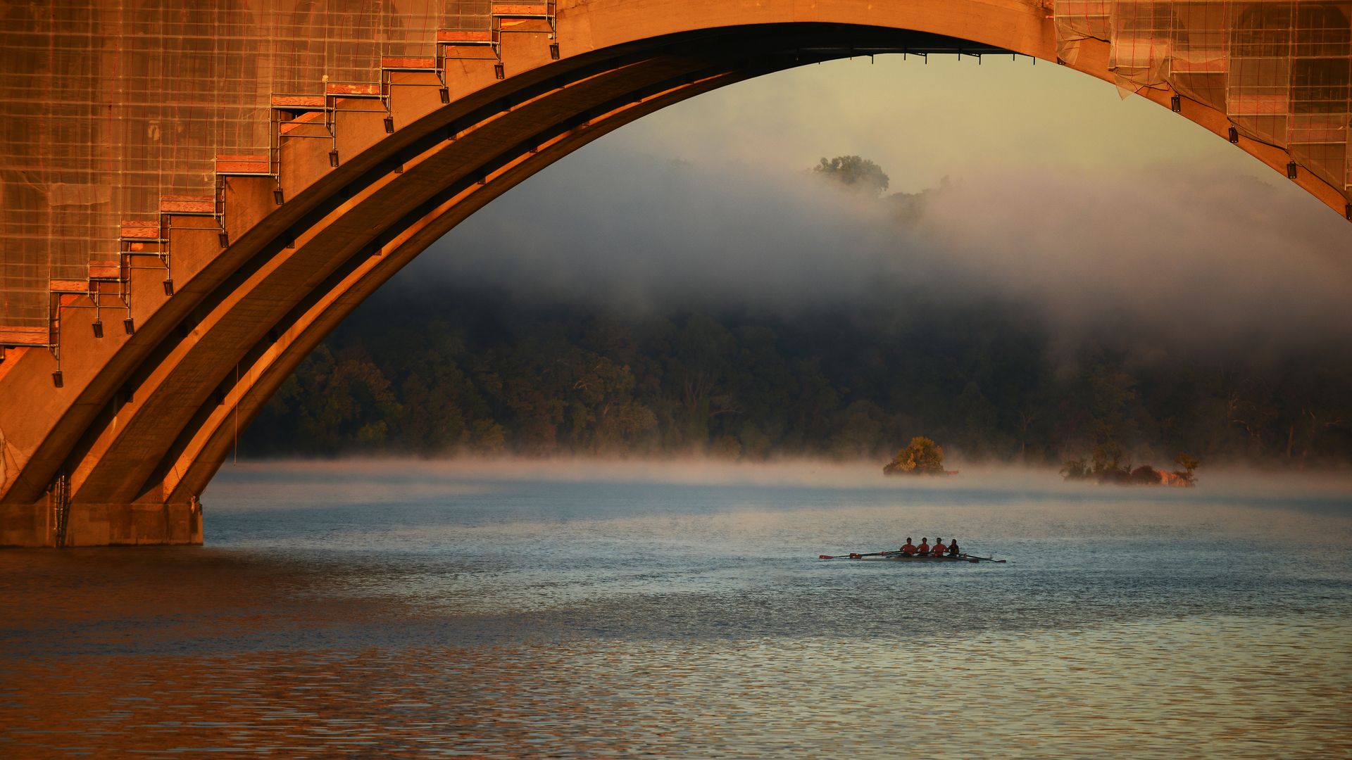 Rowers on the Potomac River, just past the Key Bridge with the rocky Three Sisters islands in the background