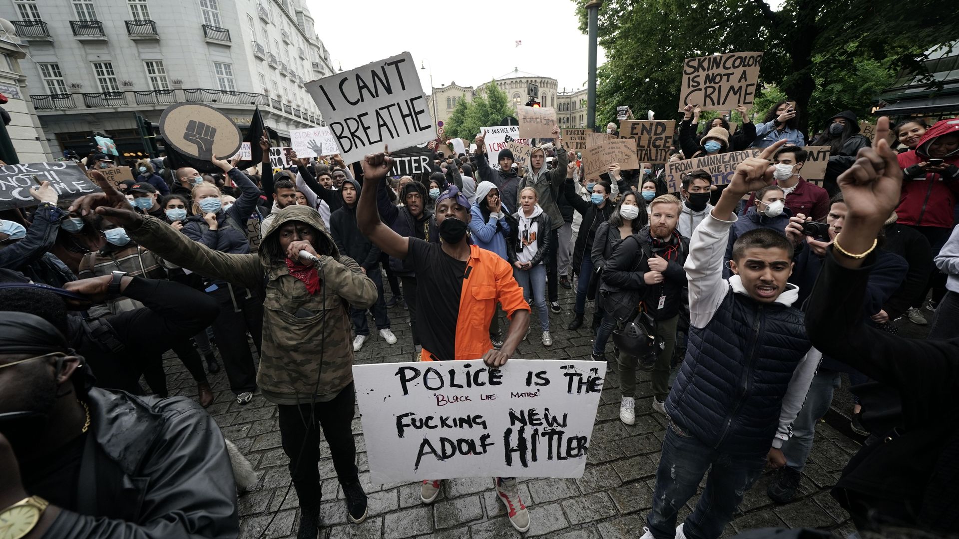 Photo of protesters holding signs that denounce racism and police brutality