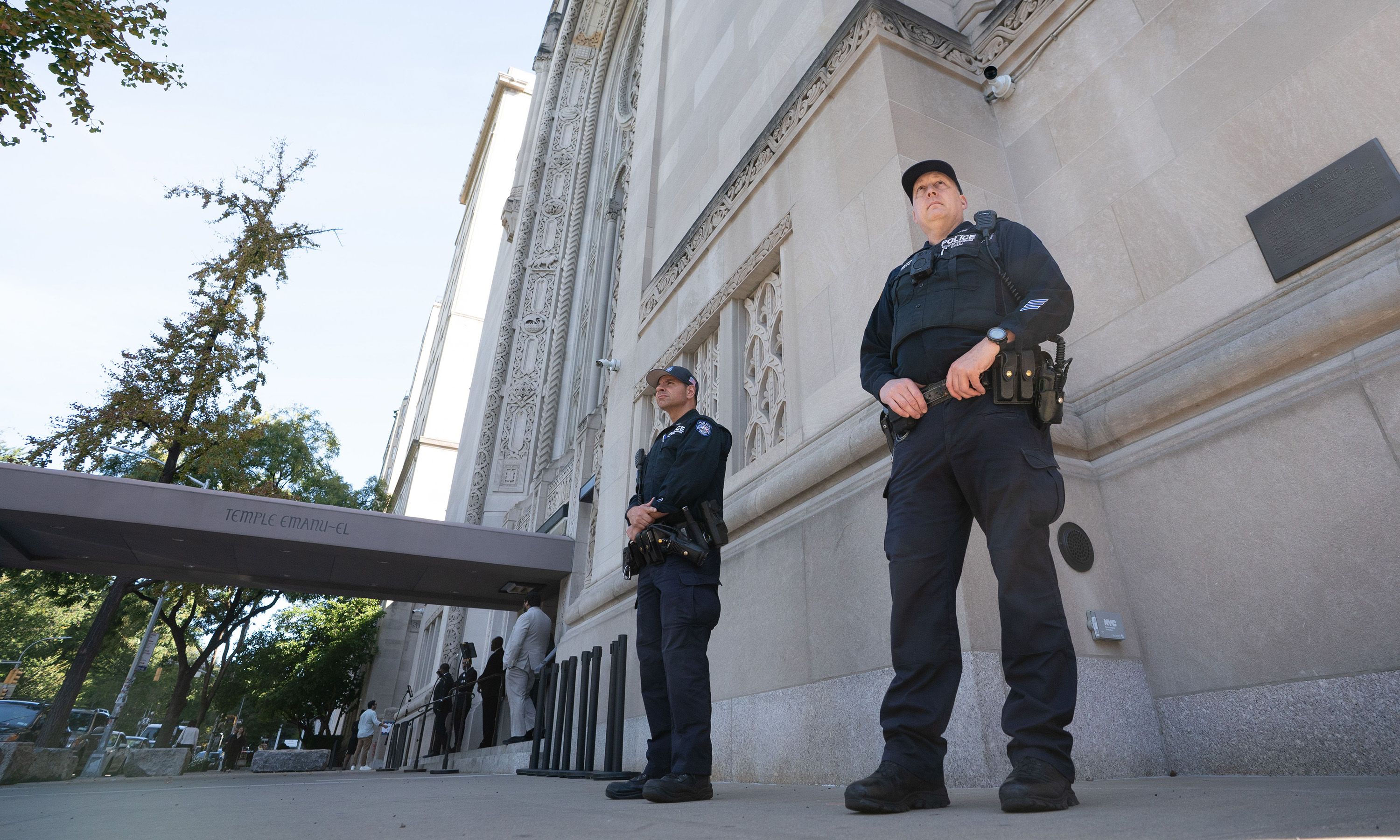 Two law enforcement officers stand outside a synagogue entrance