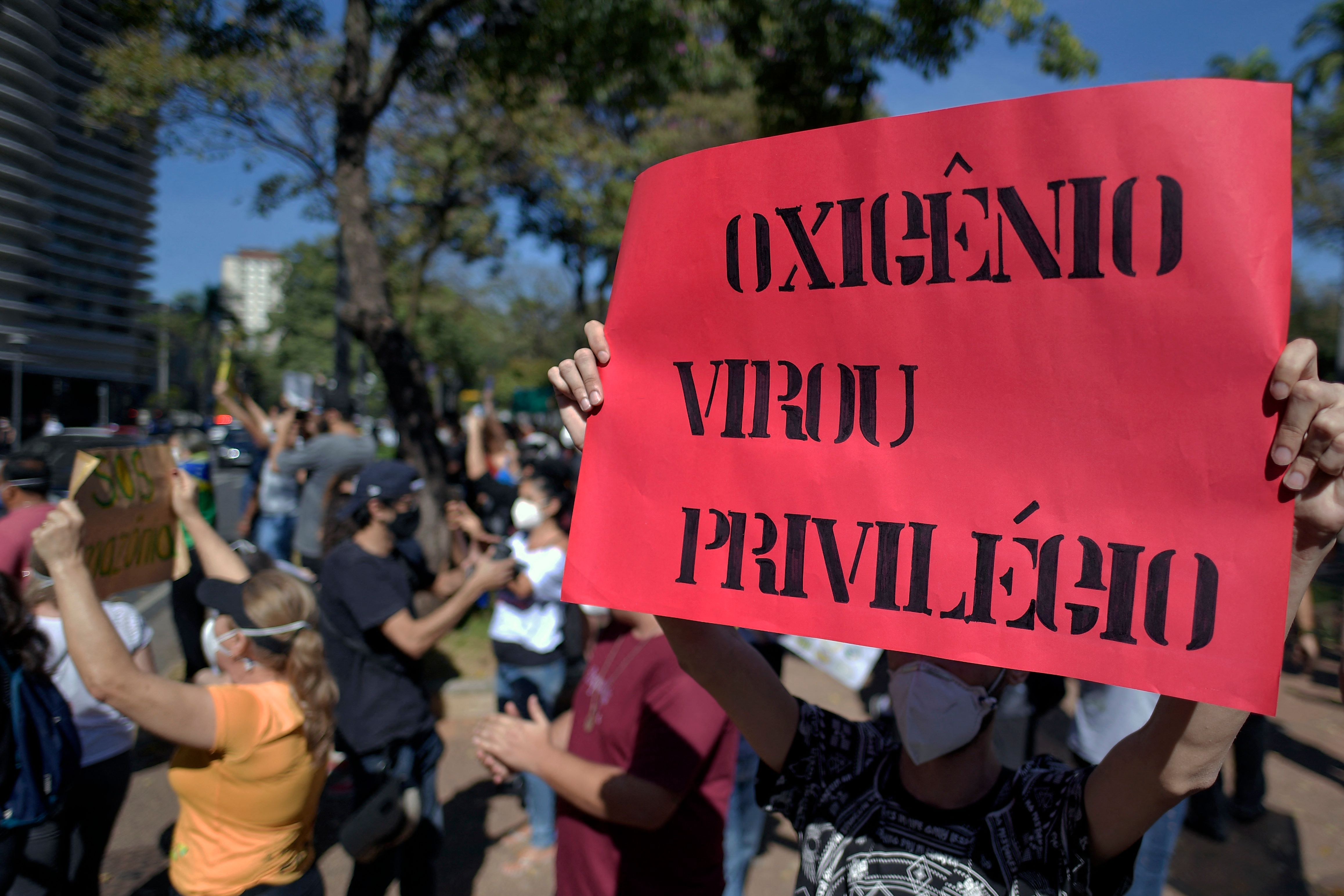 A demonstrator holds a sign reading Oxygen became a priviledge during a protest against Brazilian President Jair Bolsonaro'at the Praca da Liberdade in Belo Horizonte, Brazil on May 29