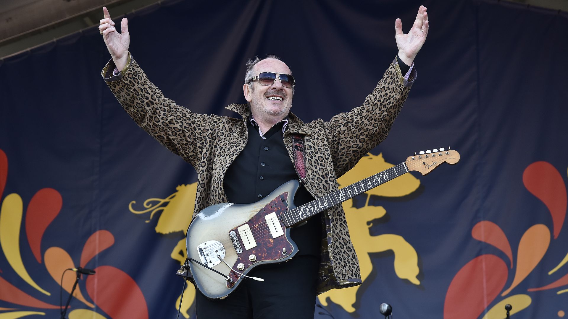 Man with guitar and arms raised