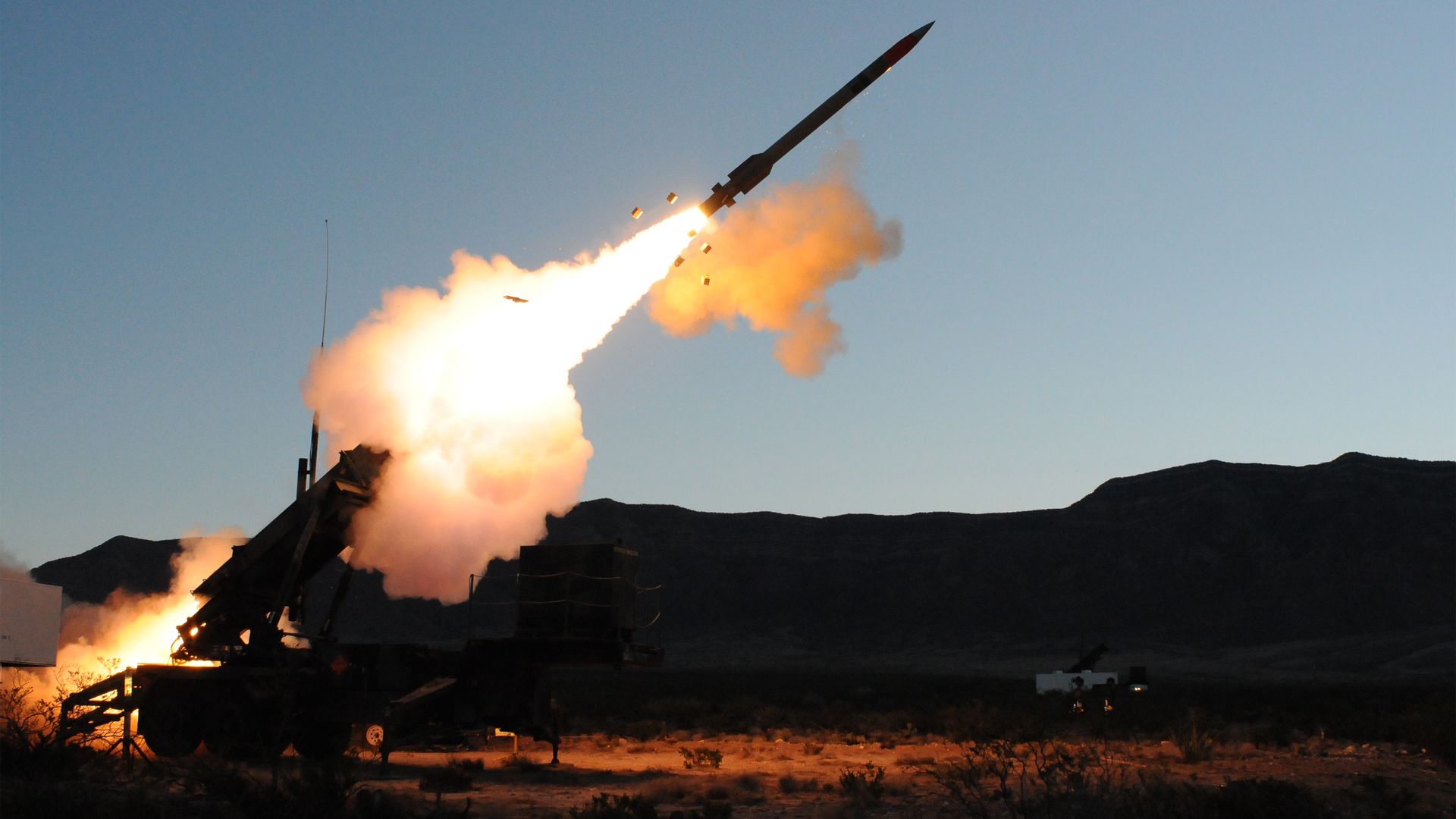 An interceptor rockets out of its launcher. White smoke and orange fire are seen. The scene itself is backlit.