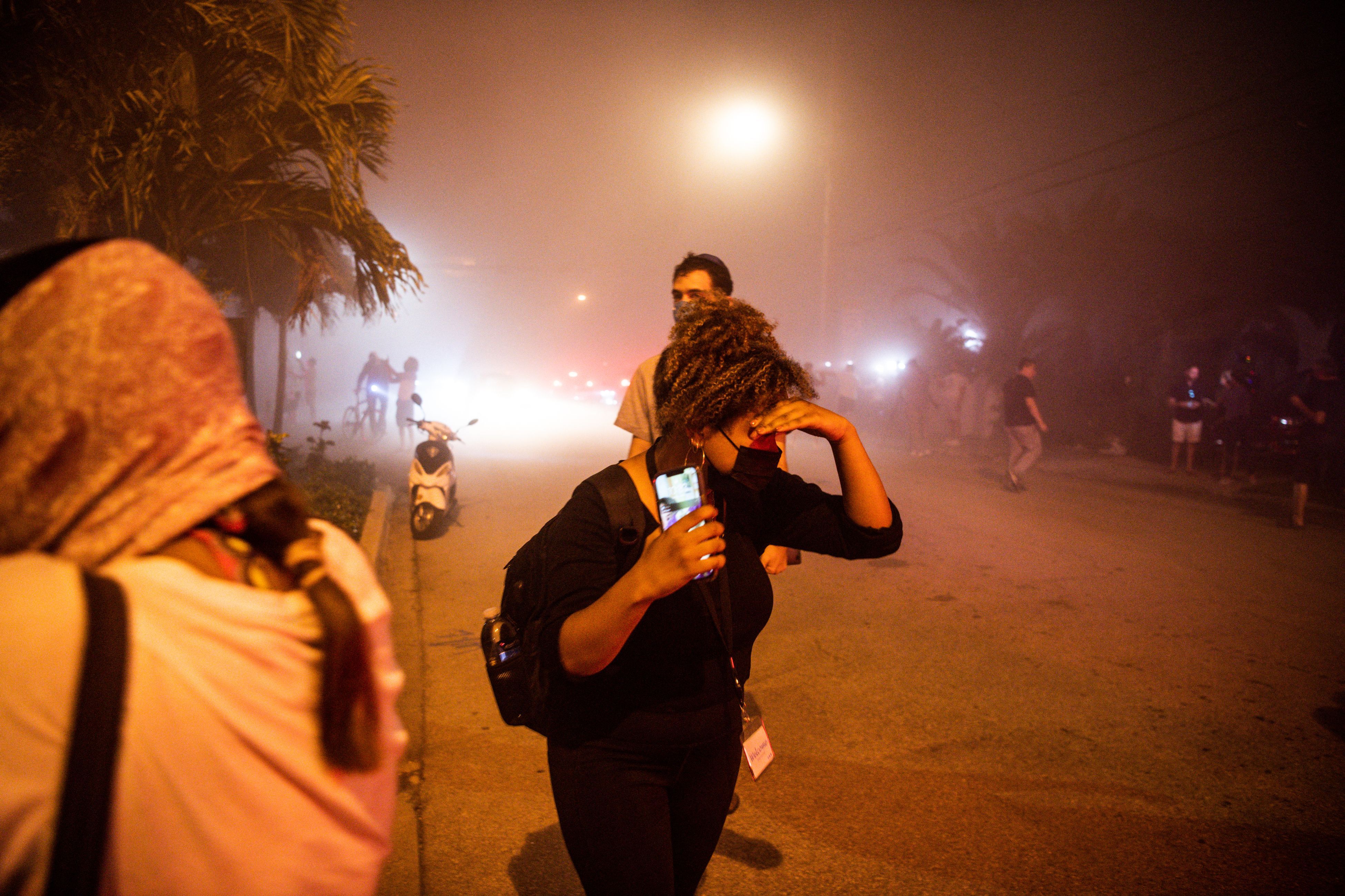  People cover their faces in a cloud of dust after watching the rest of the Champlain South tower being demolished by a controlled explosion in Surfside, Florida, north of Miami Beach, late on July 4