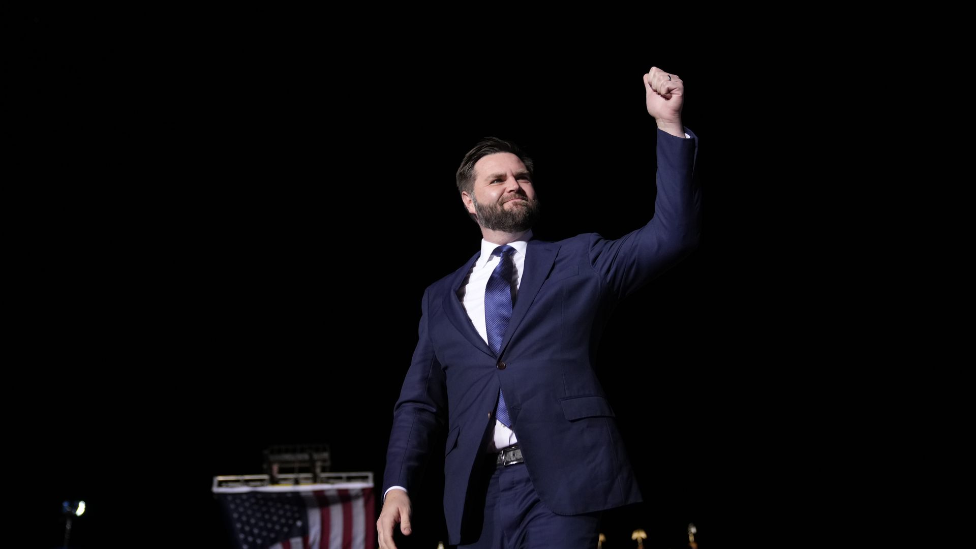 J.D. Vance walks on stage at a political rally. 