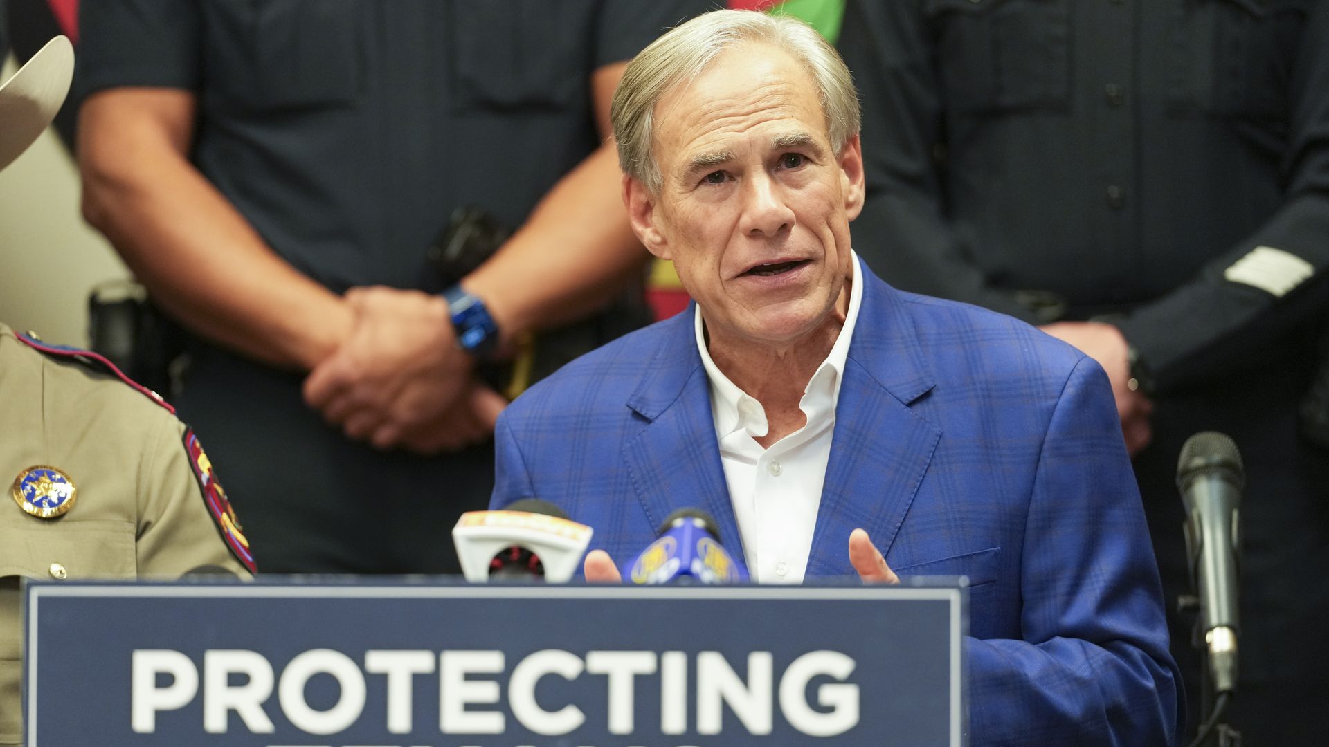 Photo of a man sitting behind a podium that says "Protecting Texans" 