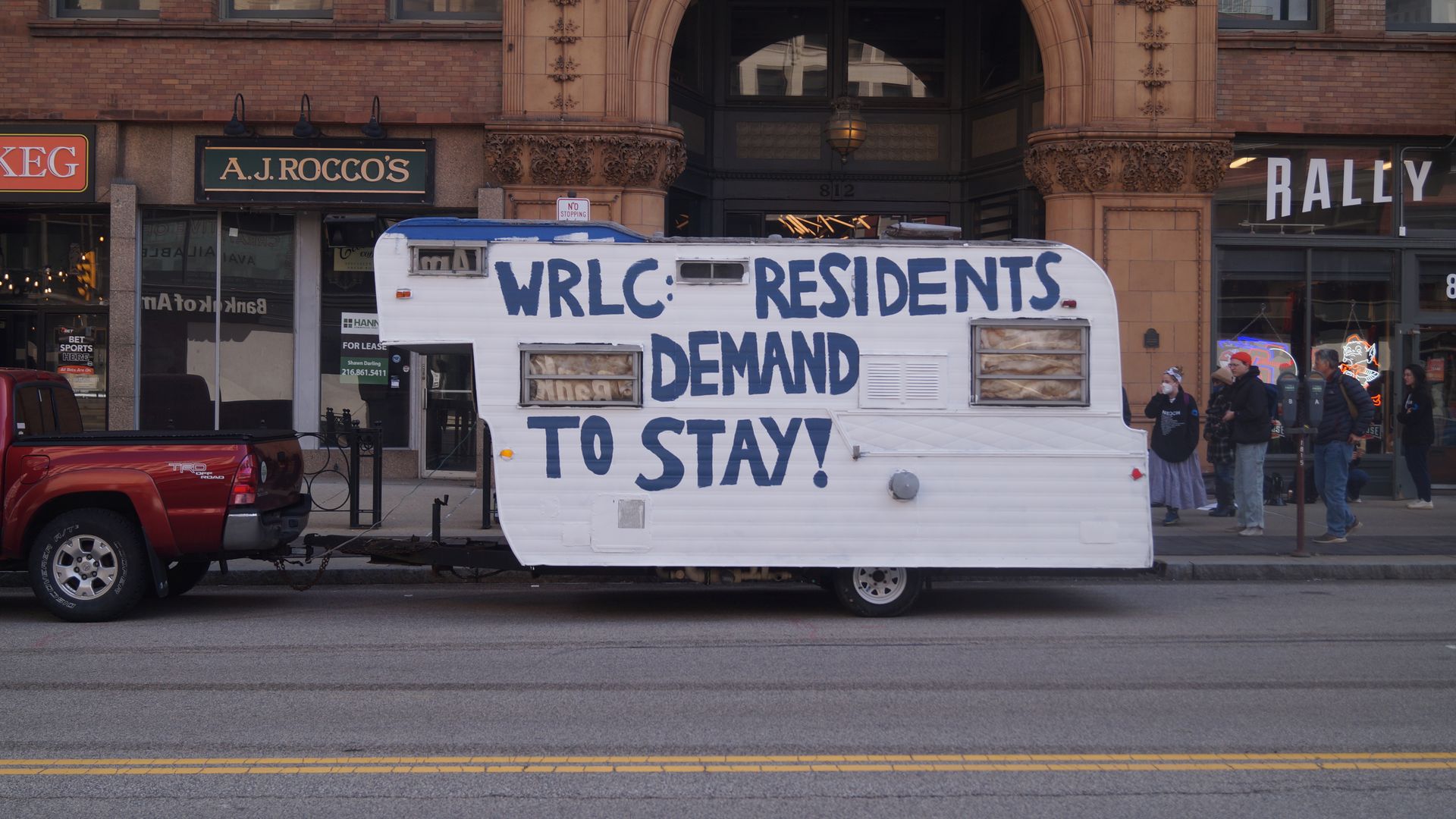 A trailer painted with blue letters: "WRLC: Residents Demand to Stay!" 