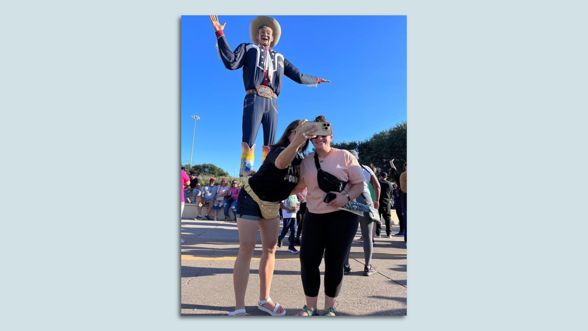 A photo of two people taking a selfie in front of Big Tex