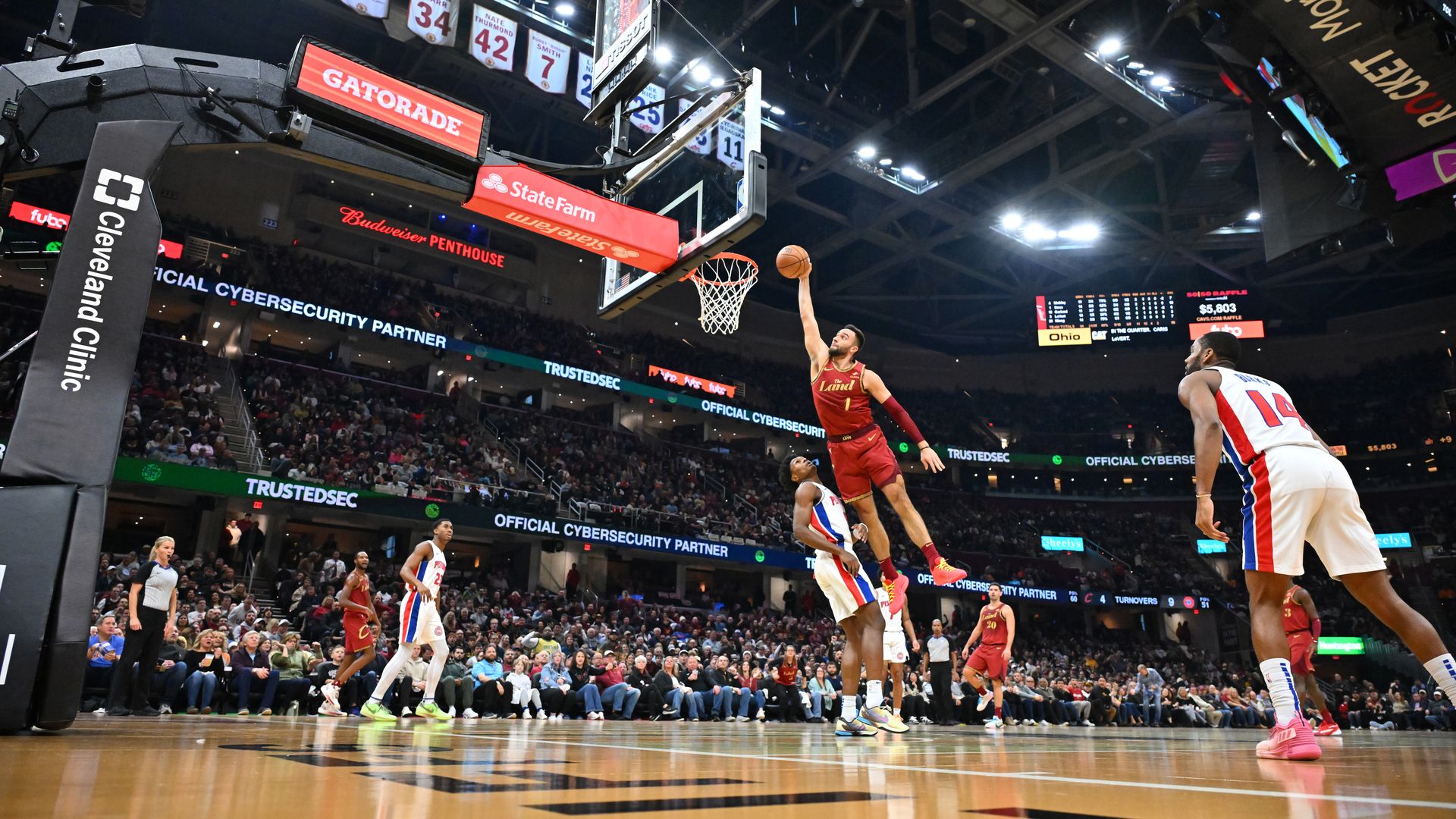 Max Strus in red jersey dunking basketball on Detroit Piston in white jersey 