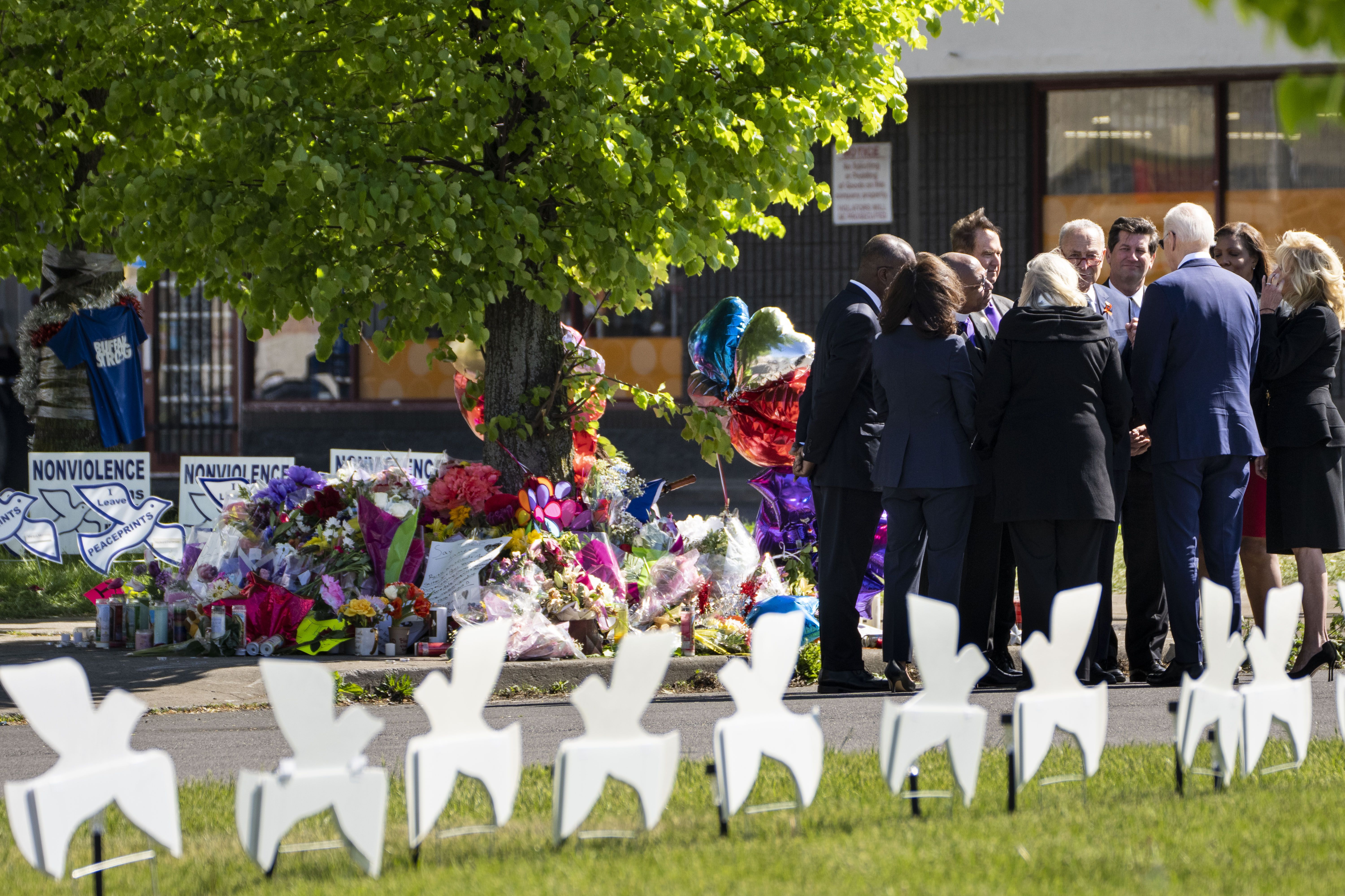 President Biden and government officials are seen standing next to a memorial to the Buffalo shooting victims.