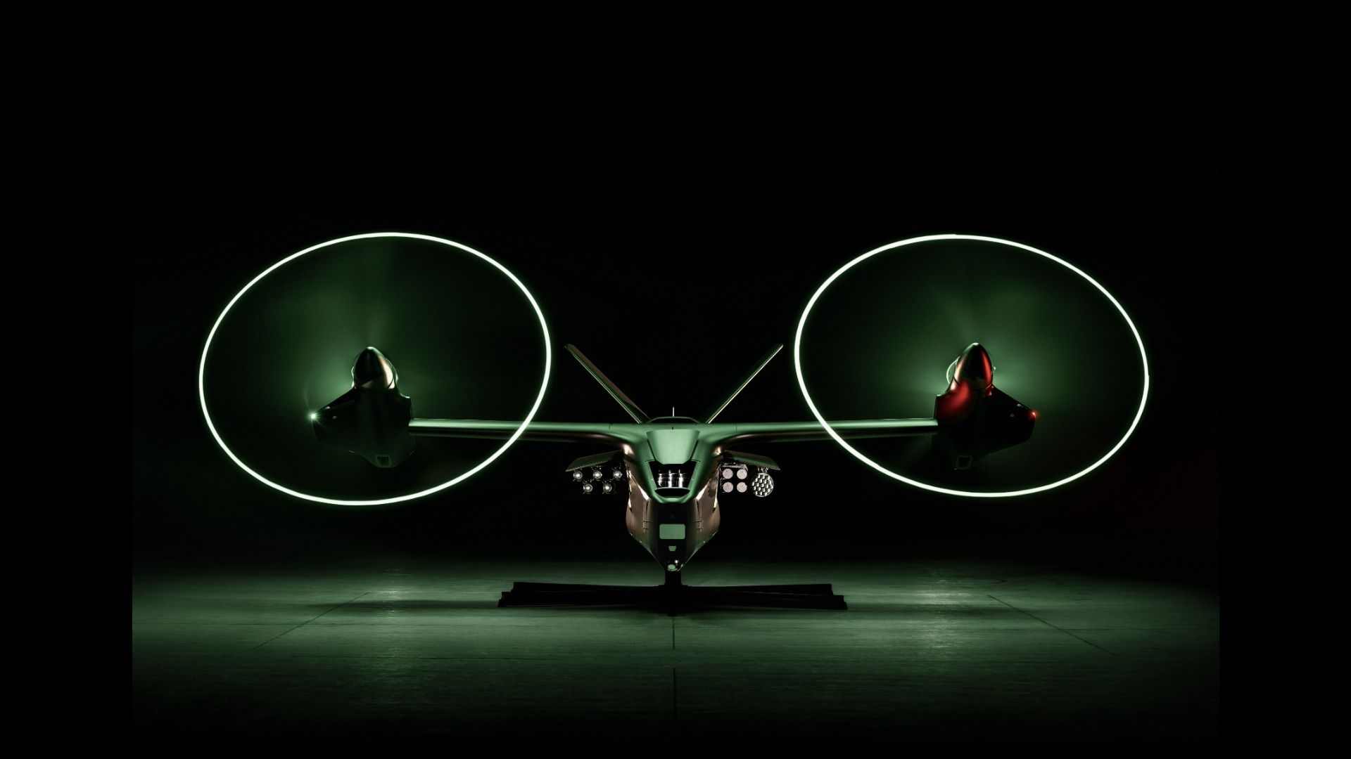 A futuristic-looking aircraft with two large glowing rotors, a sleek central fuselage, and a dark hangar backdrop.