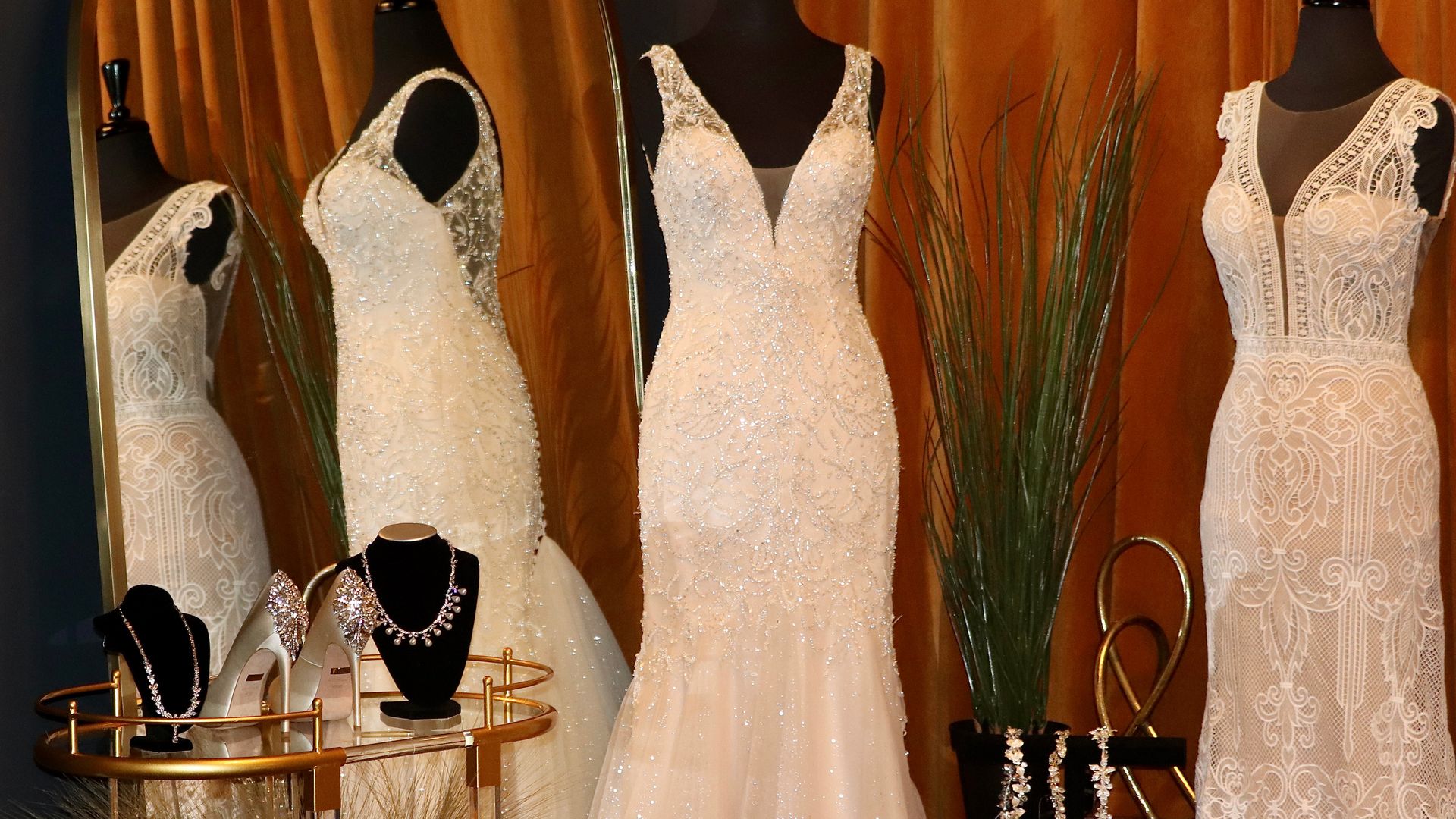 Wedding dresses hang on mannequins in a showroom.