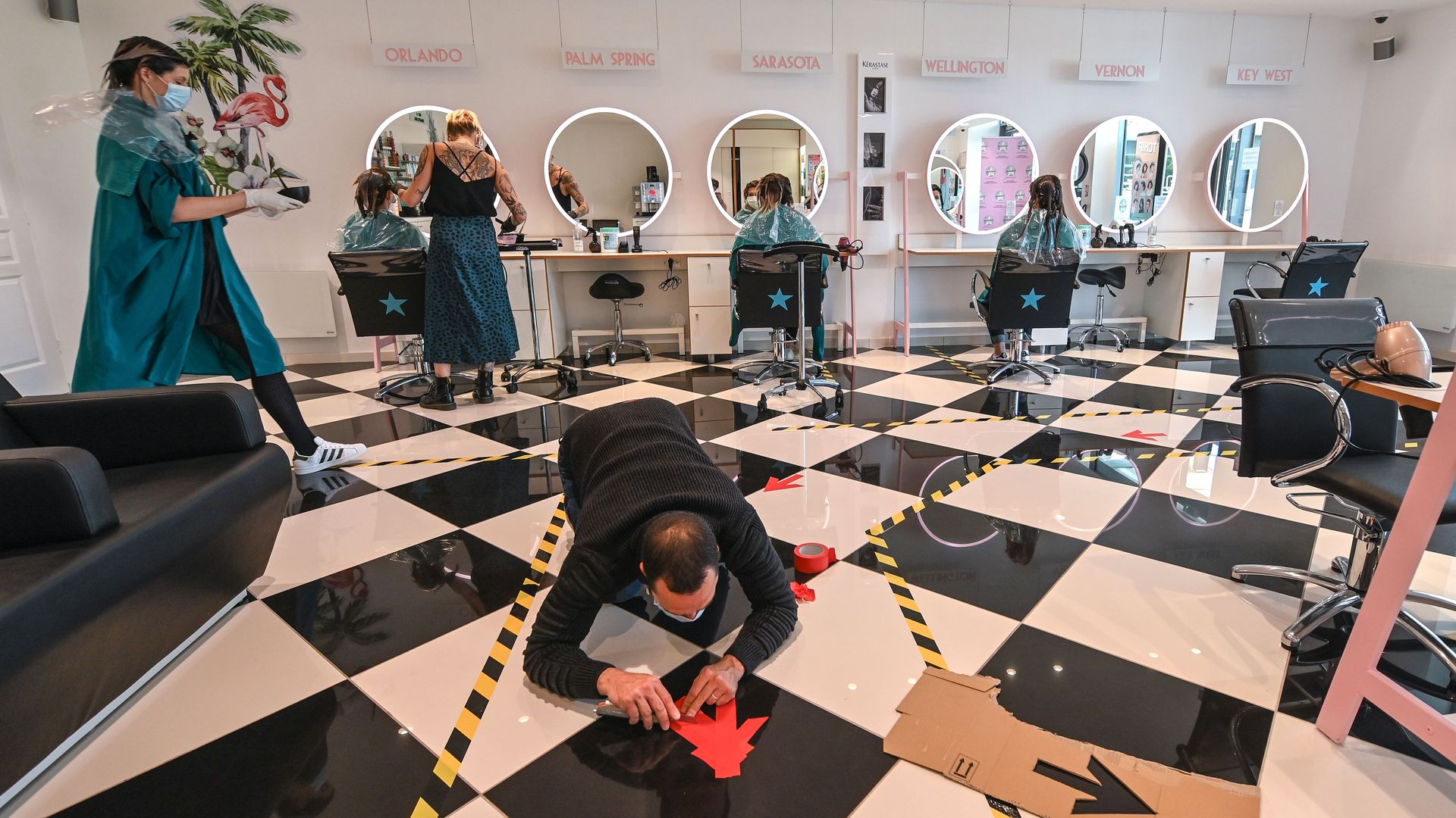 Members of staff visit the Tchip hair dressing salon which is carrying out a test run with the use of face masks and markers on the floor 