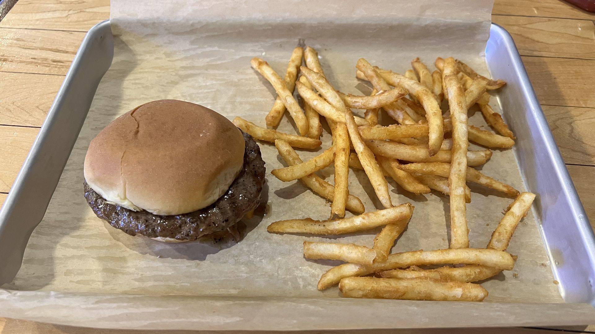 A burger on a tray next to a side of fries