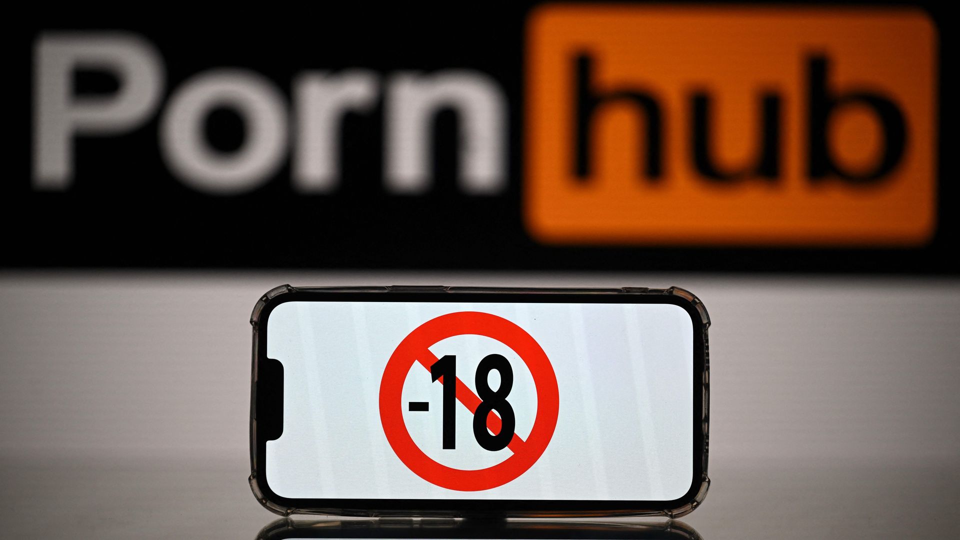 A phone displaying a "no one under 18" symbol in front of a PornHub logo