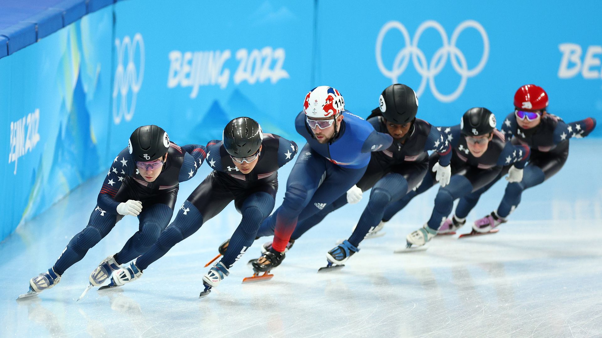Photo of Team USA short track speed skaters on the ice skating in a line formation