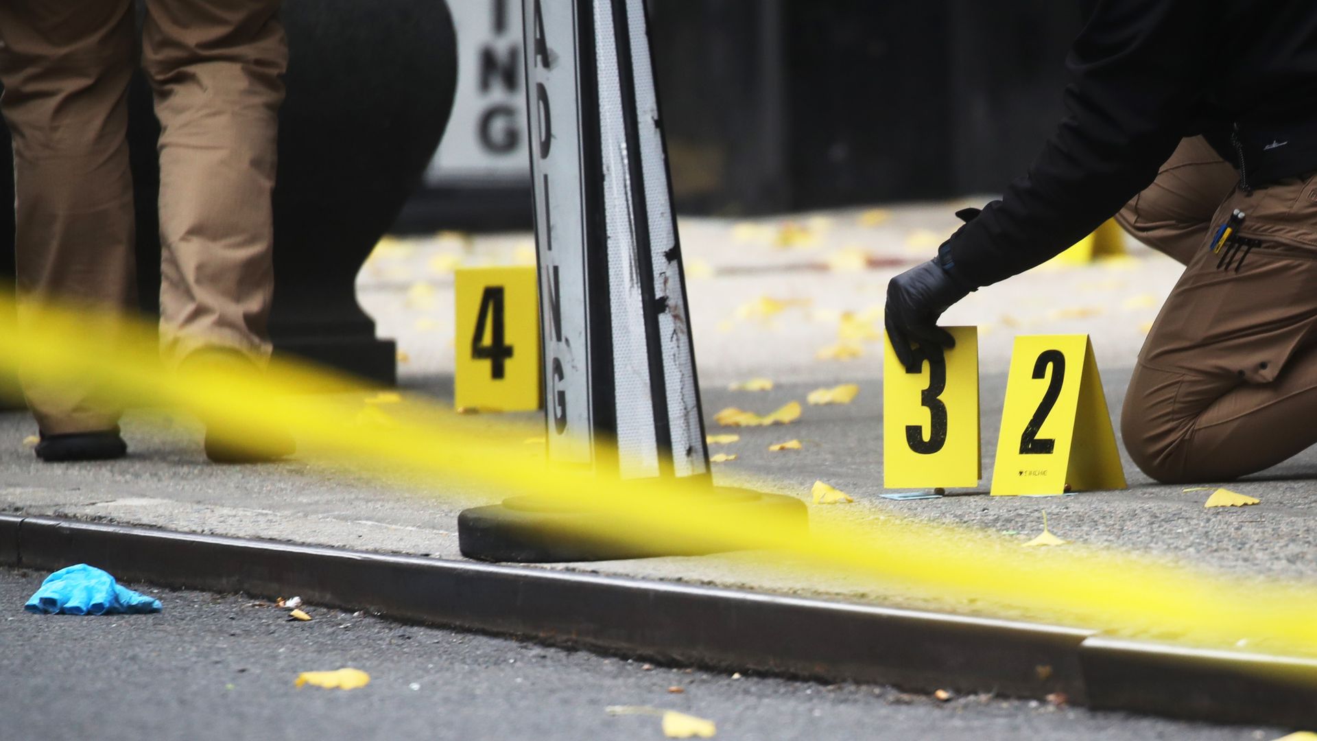 Police gather evidence at the scene of a crime, placing numbered placards on a sidewalk