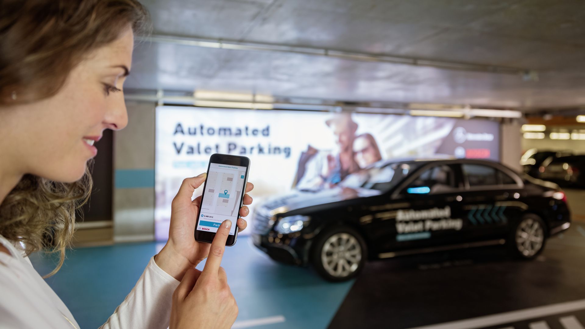 Image of a woman using a smartphone app to automatically park a car.