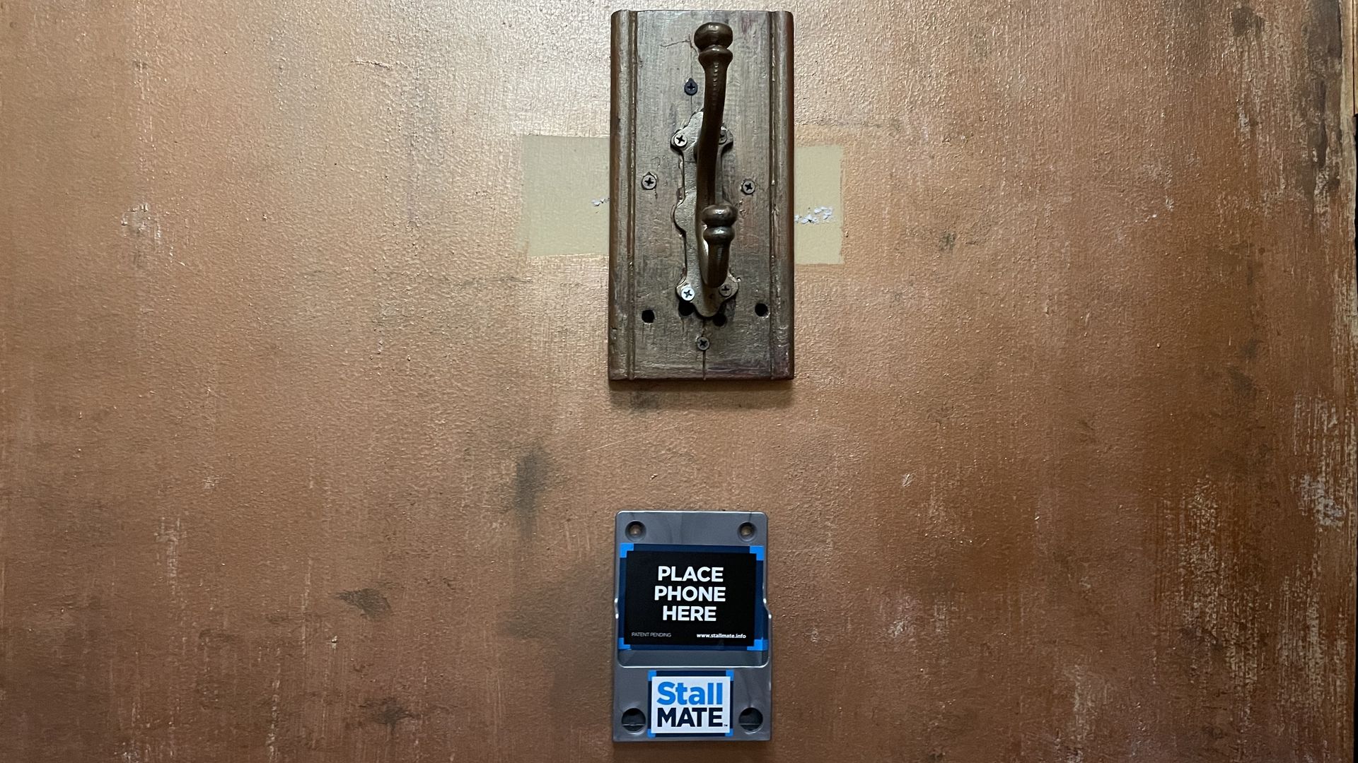 A door with a "Stall Mate" holder for your cellphone on it.