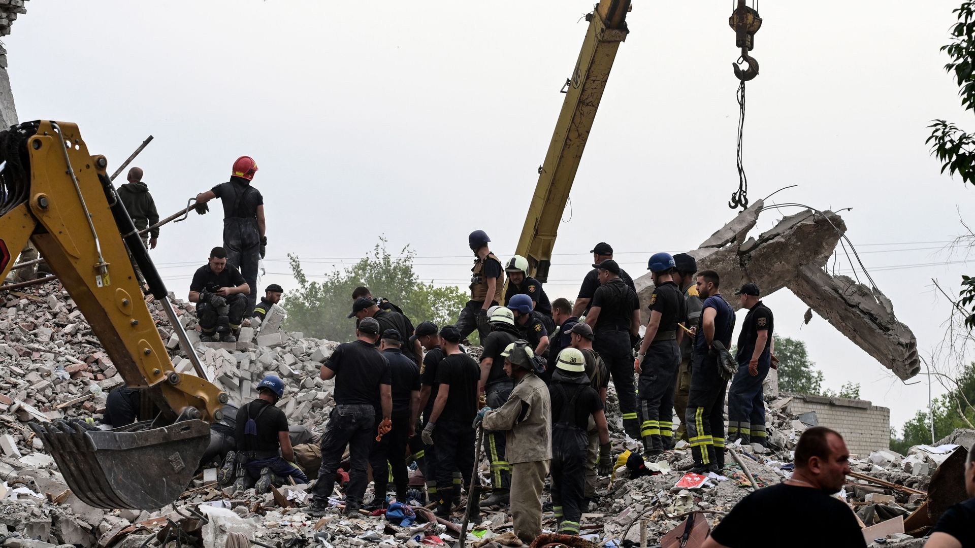 Firefighters and members of a rescue team search the debris after a building was partially destroyed following shelling, in Chasiv Yar, eastern Ukraine, on July 10, 2022.