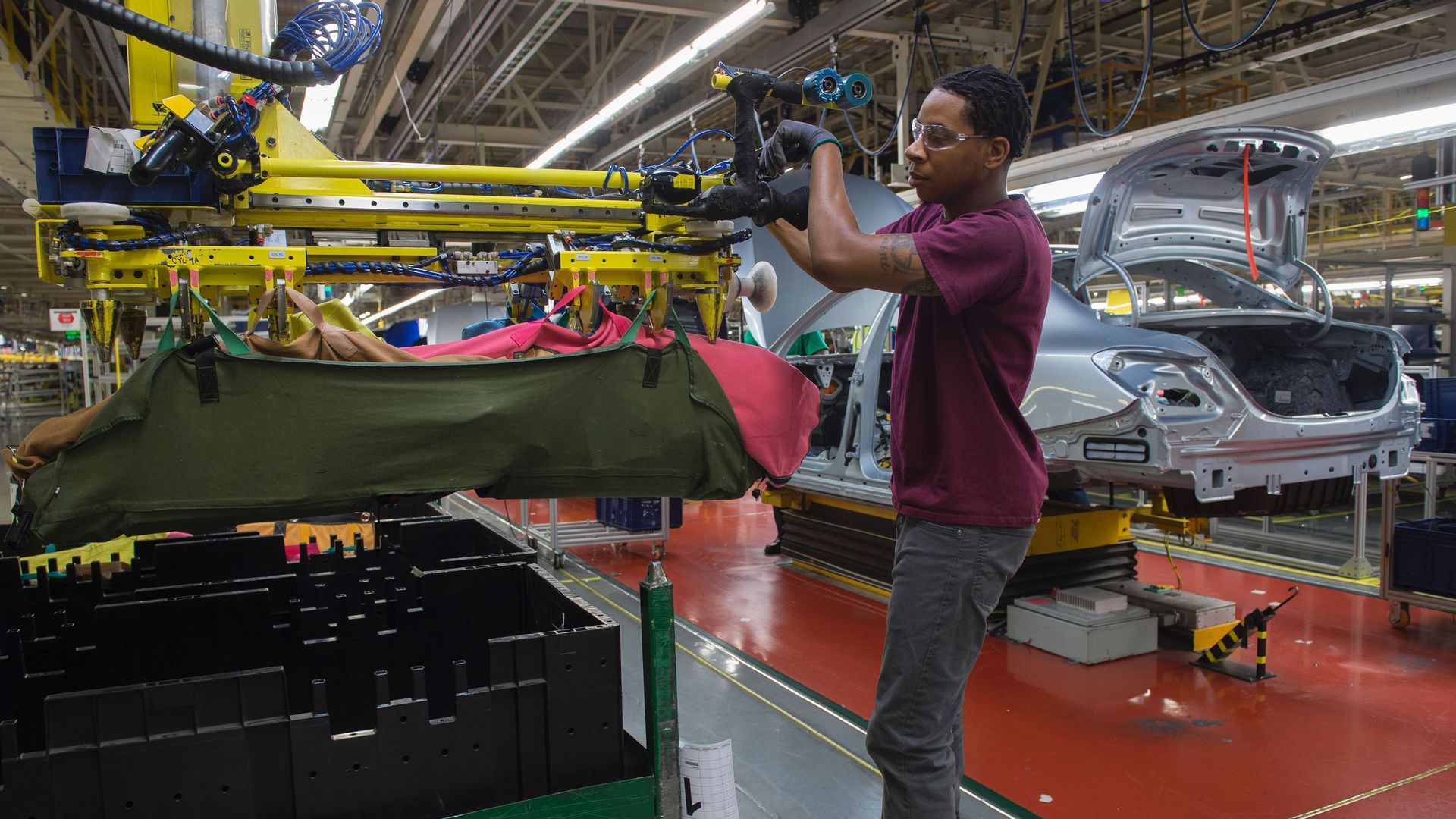 Man works on car in plant.