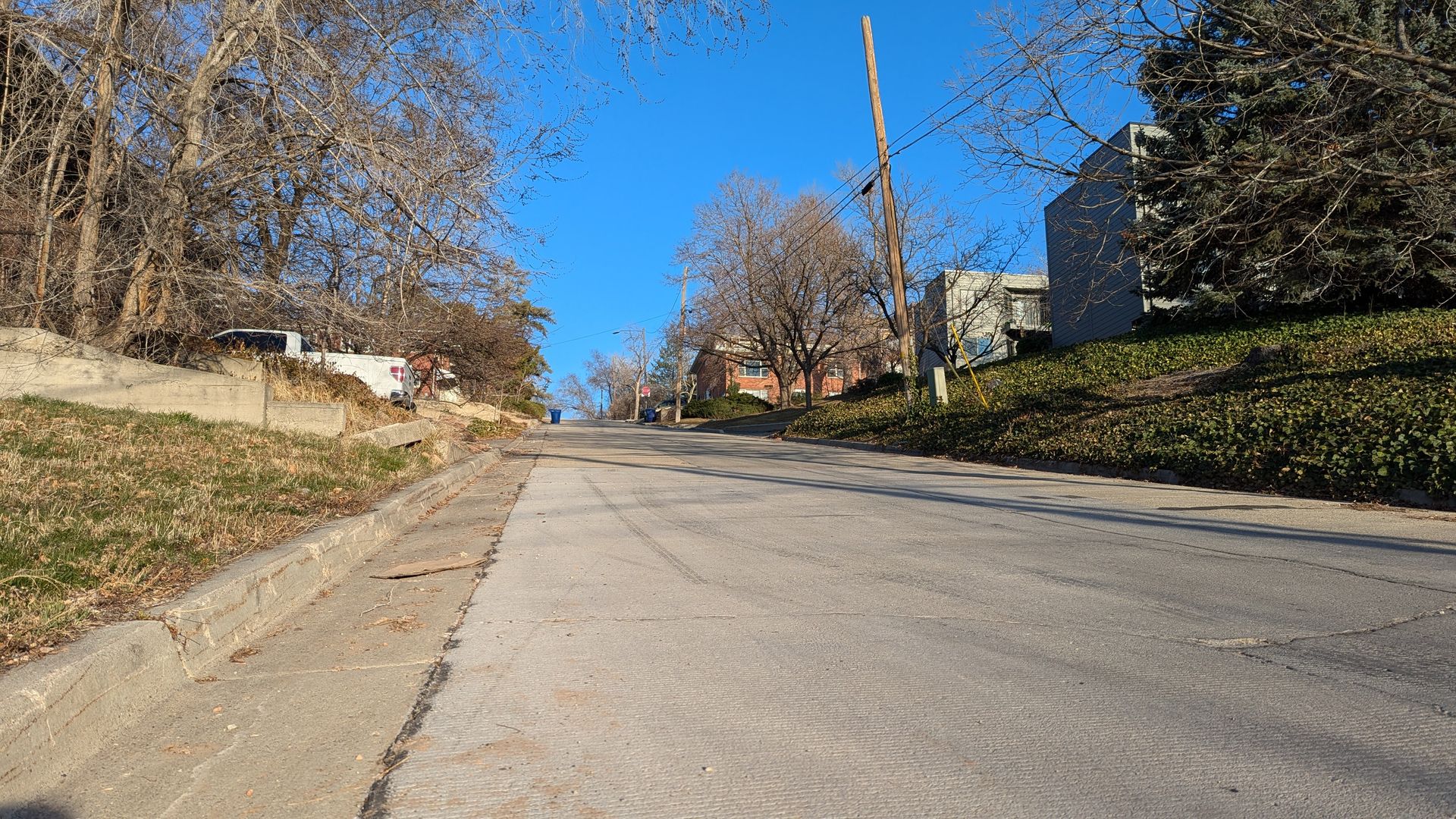 A steep residential street under a blue sky.