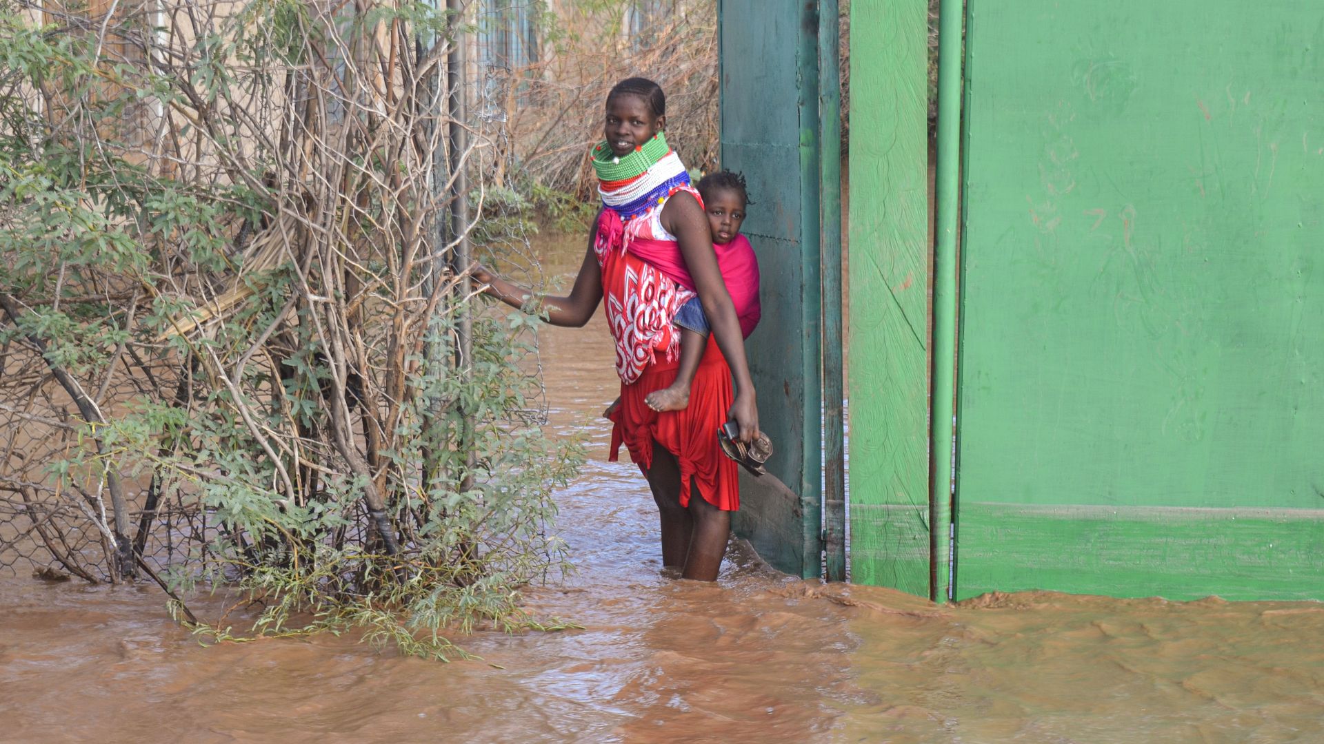 A Turkana woman stops at a gate of her house that is submerged by flooded water after heavy rain in Lodwar, northwestern Kenya on October 18, 2019. (Photo by - / AFP) (Photo by -/AFP via Getty Images)