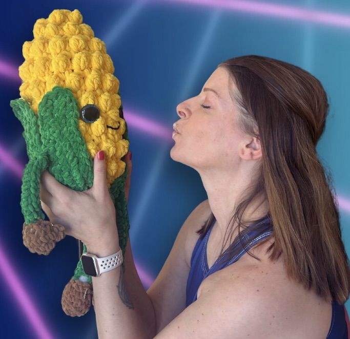 A woman holding up a corn plushie