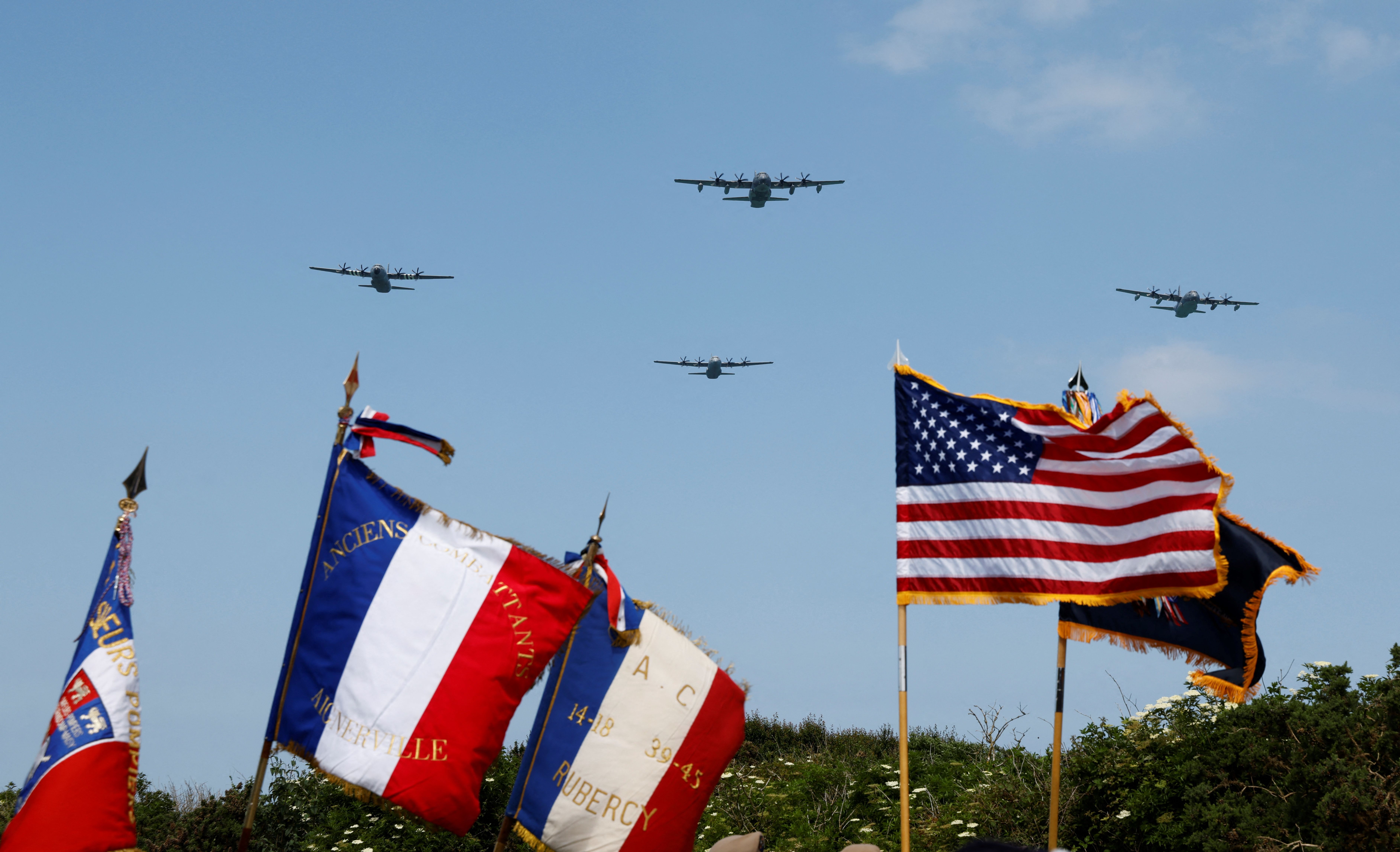 Lockheed C-130 Hercules aircraft overfly flags on "Pointe du Hoc" clifftop in Cricqueville-en-Bessin, France, on June 5.