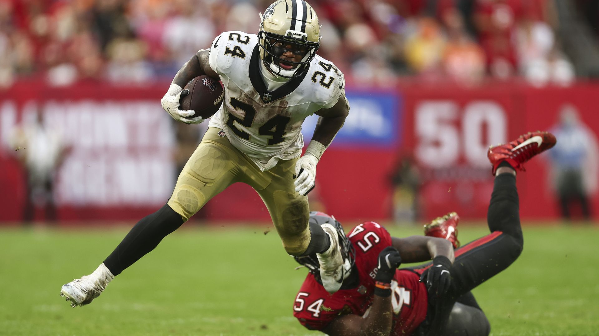 A New Orleans Saints player slips away from a Bucs defender, who has fallen to the ground. 