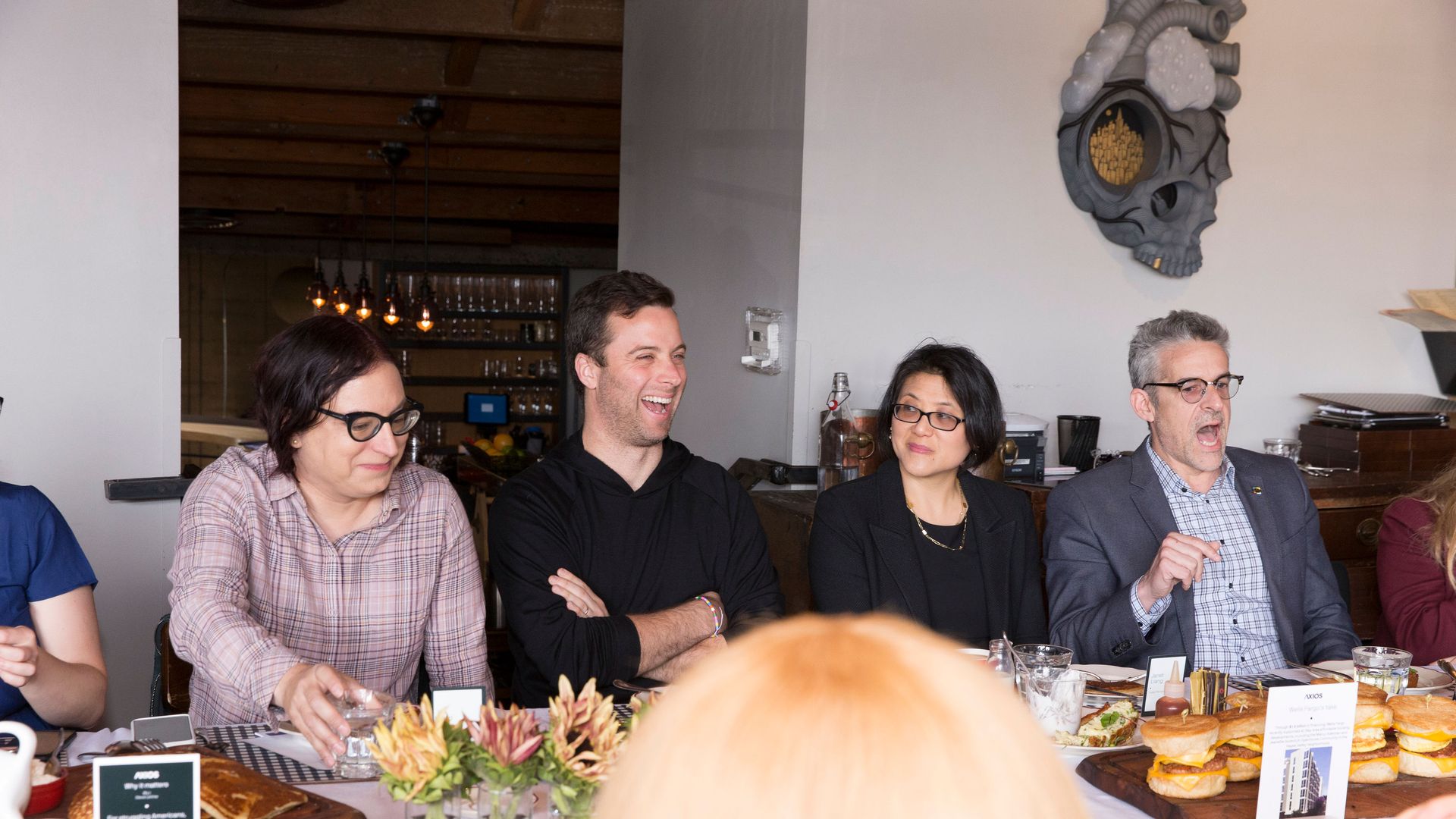 Roundtable participants sit around the table, four are seen laughing.