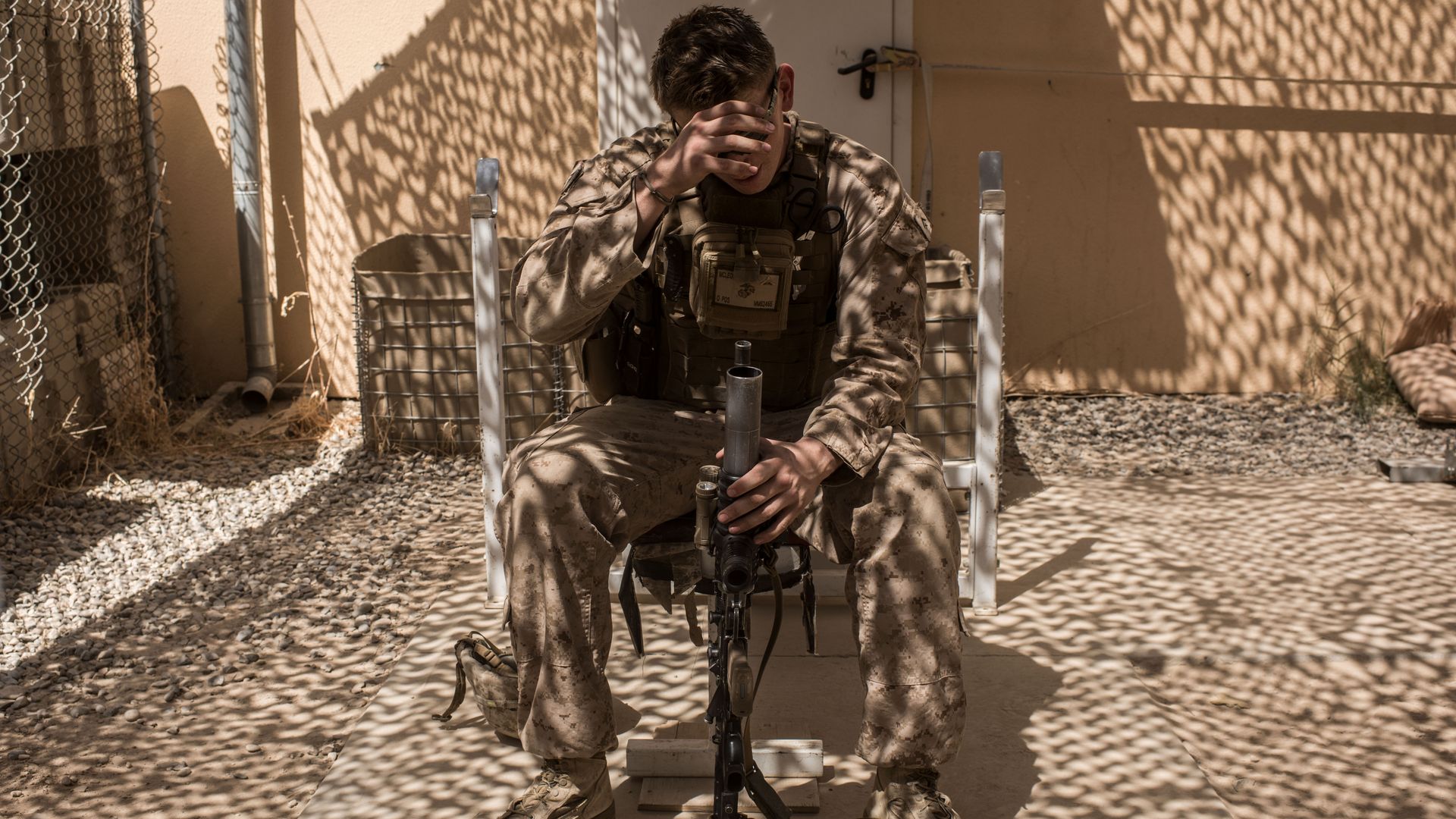 A U.S. soldier sits in a chair holding his gun.