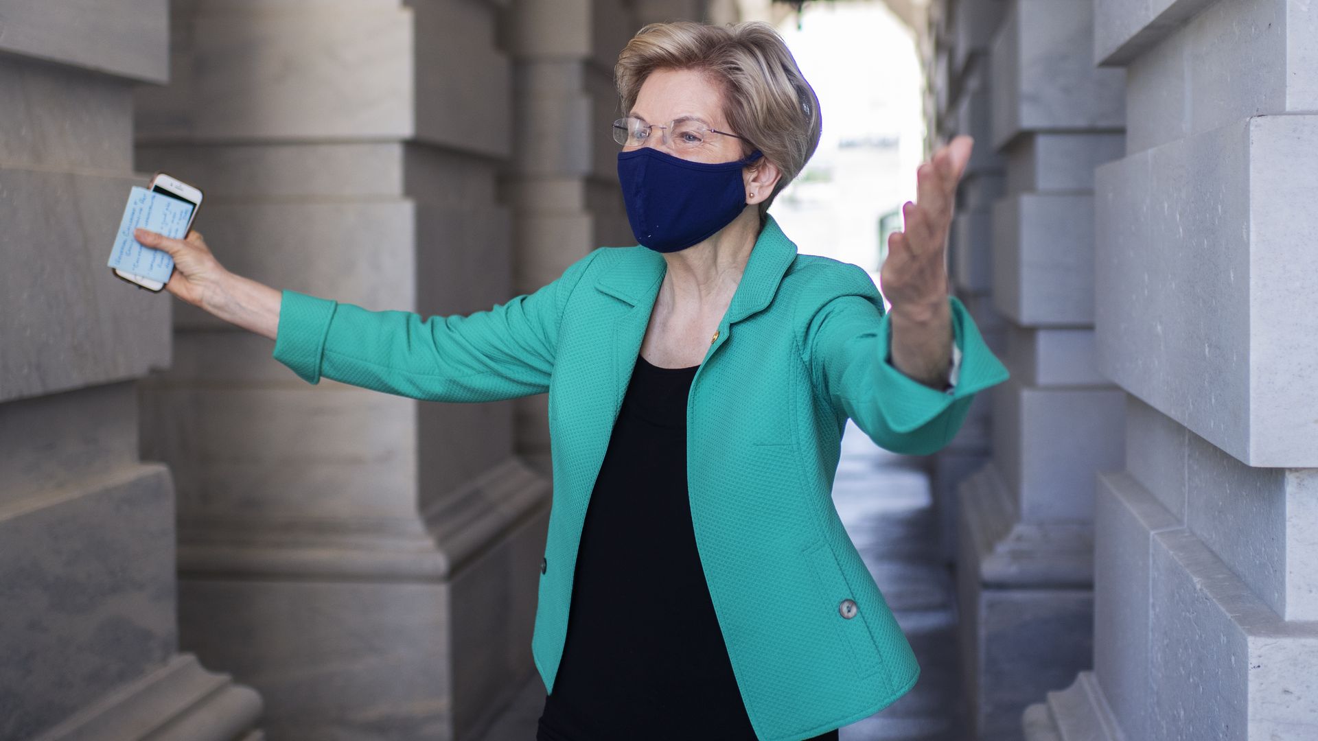 Elizabeth Warren stands with arms outstretched 