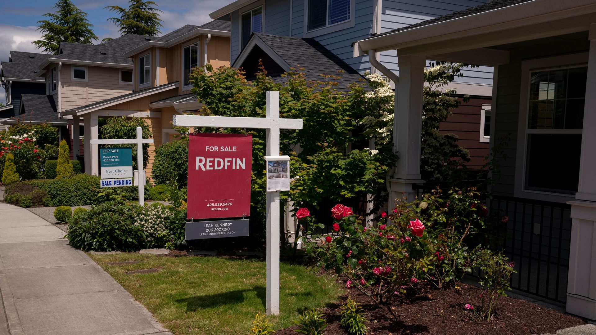 A street in Seattle with several houses that have for sale signs on them.