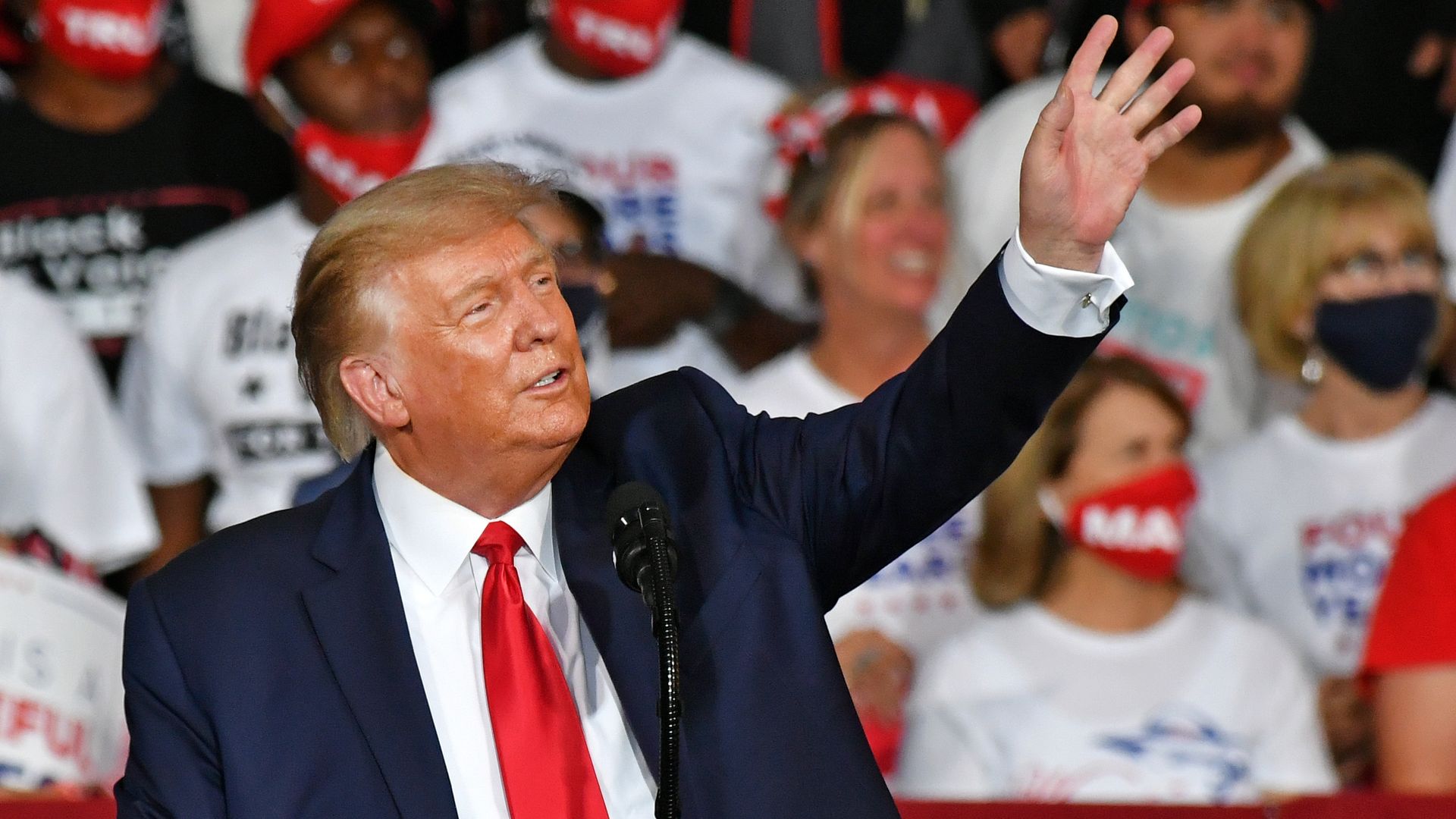 Trump reaches out a hand in a wave while speaking to supporters at a rally