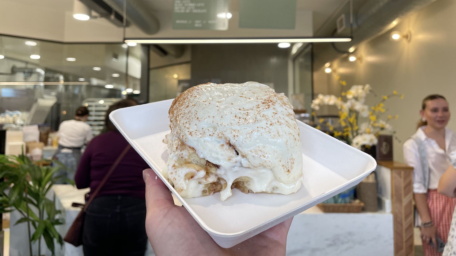 a cinnamon roll being held in the air on a plate