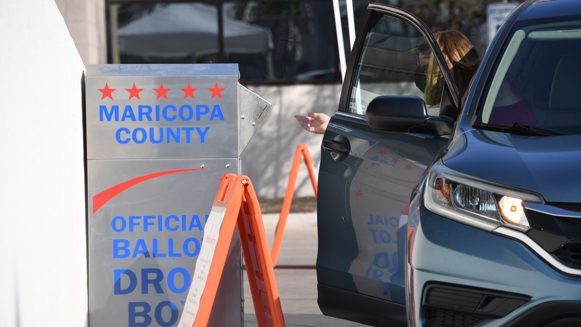 People deposit their mail-in ballots for the US presidential election at a ballot collection box in Phoenix, Arizona on October 18, 2020.