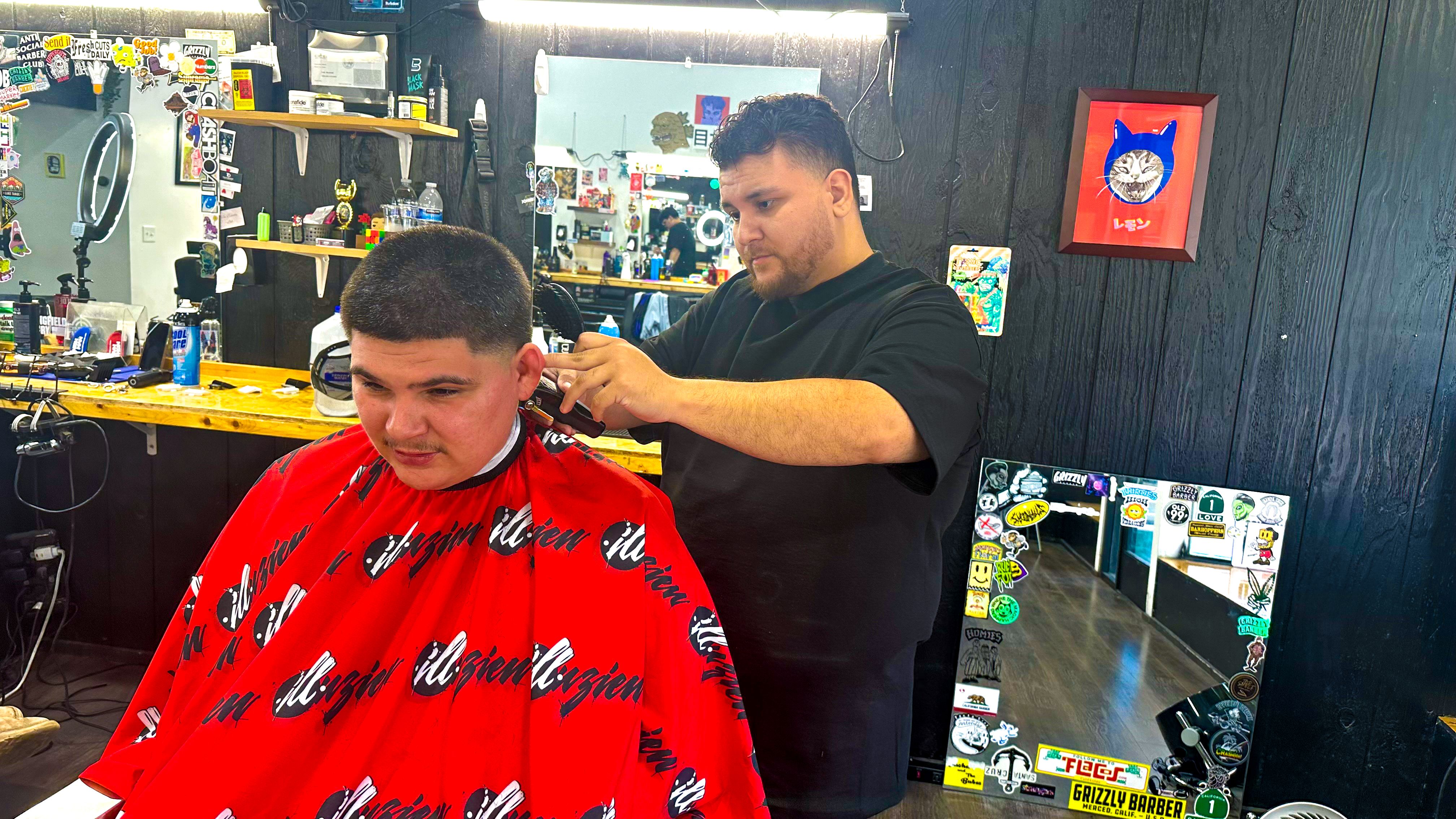 John Lomeli, 24, cuts the hair of Lawrence Sears, 26, in Grizzly Barber in Merced, California. Lomeli is voting for Trump because of the economy and Sears says he is open to voting for Harris. 