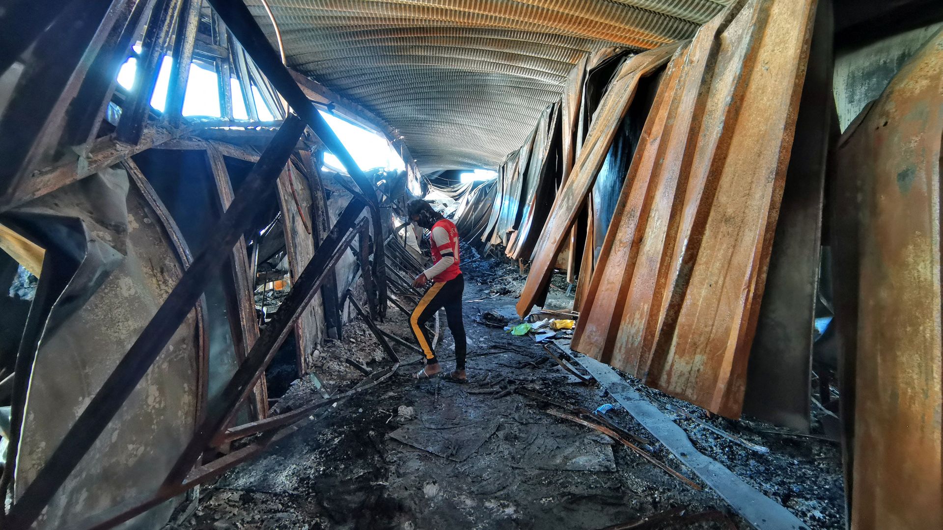 A man looks through the burnt remains of the ravaged coronavirus isolation ward of Al-Hussein hospital in the southern Iraqi city of Nasiriyah
